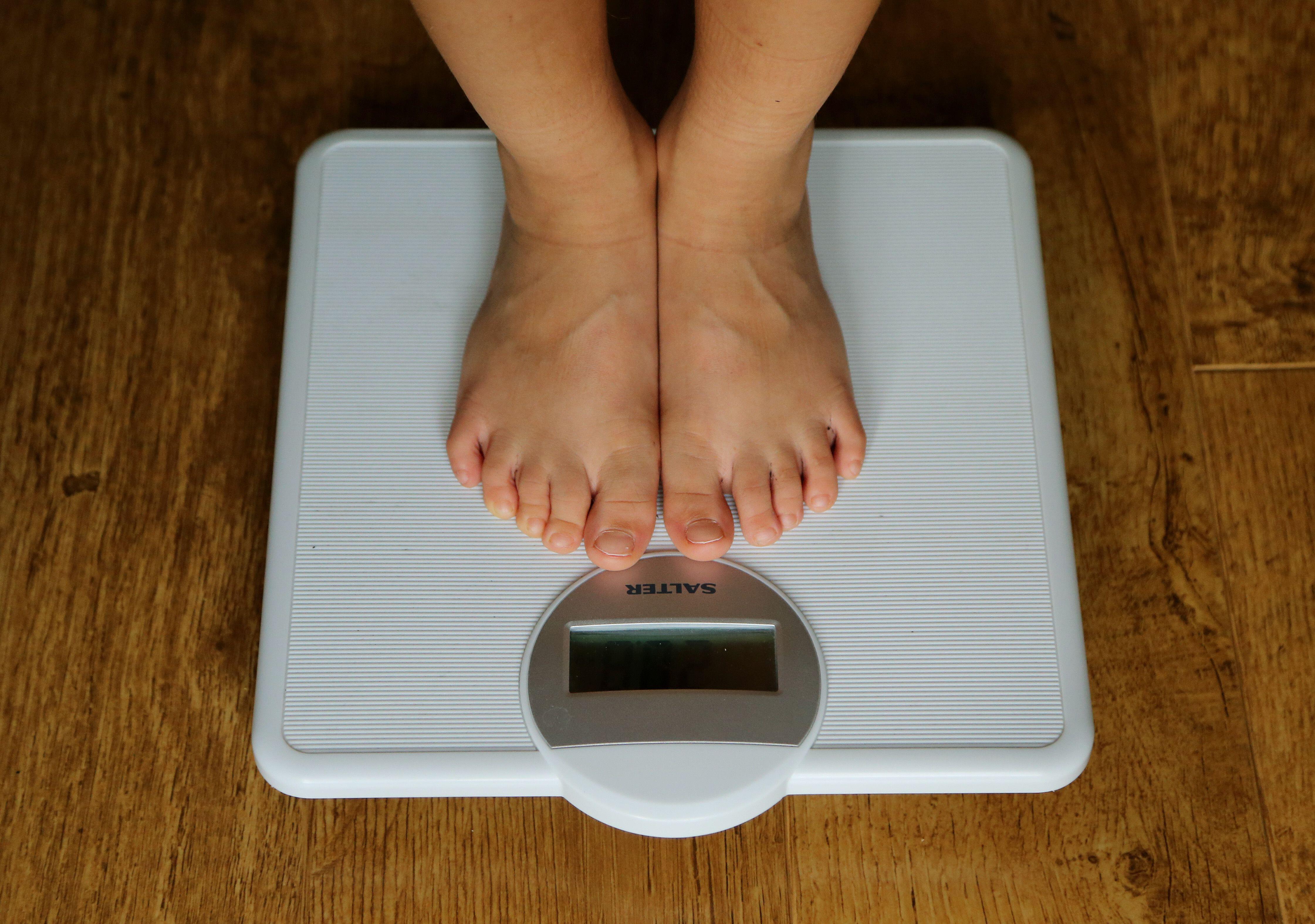 Close up photo of a person’s feet standing on weight scales (Alamy/PA)
