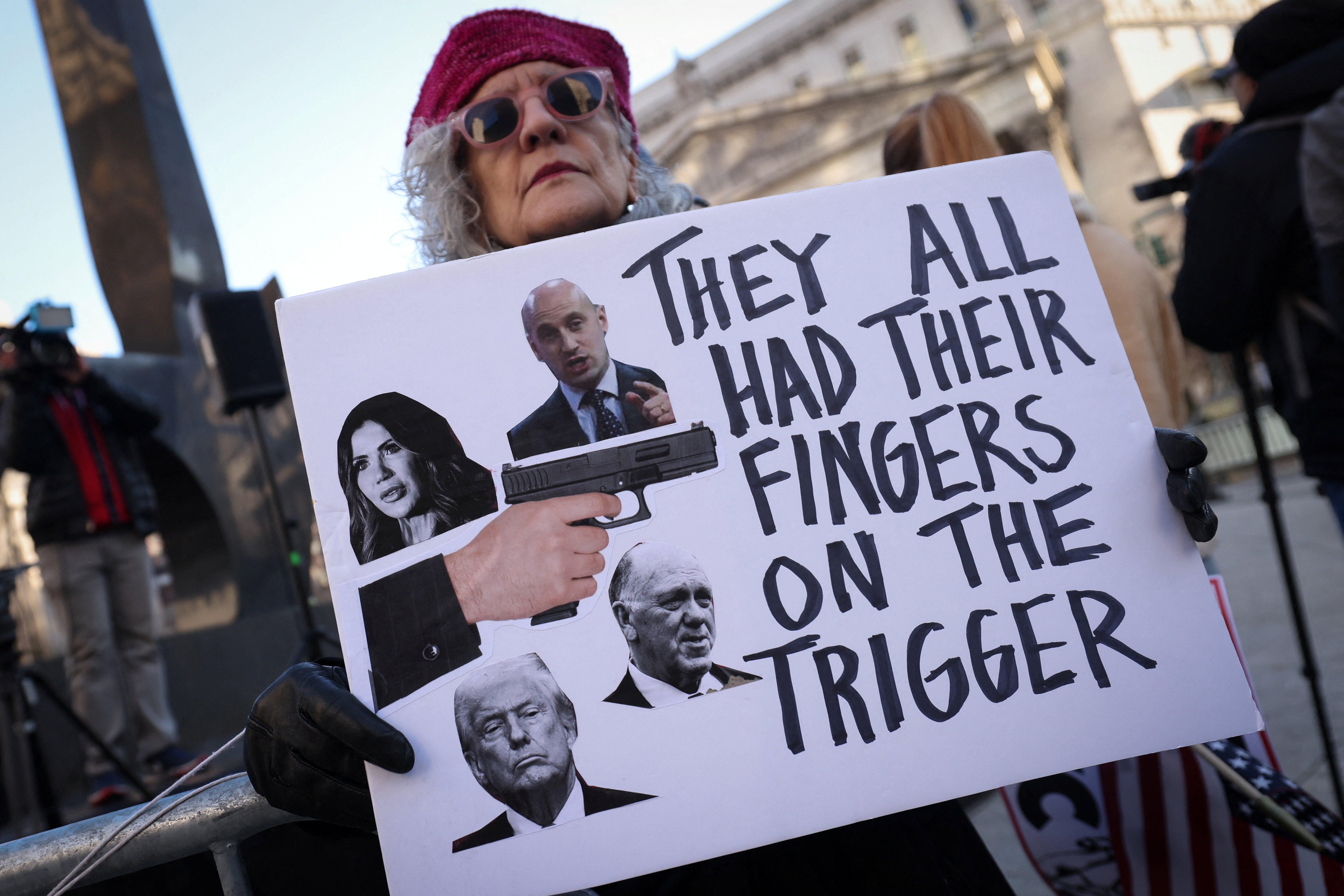 A protester in New York holds a sign blaming top administration officials for the killing of Renee Nicole Good