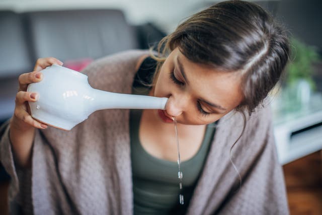 <p>A young woman using neti pot at home for nasal irrigation</p>