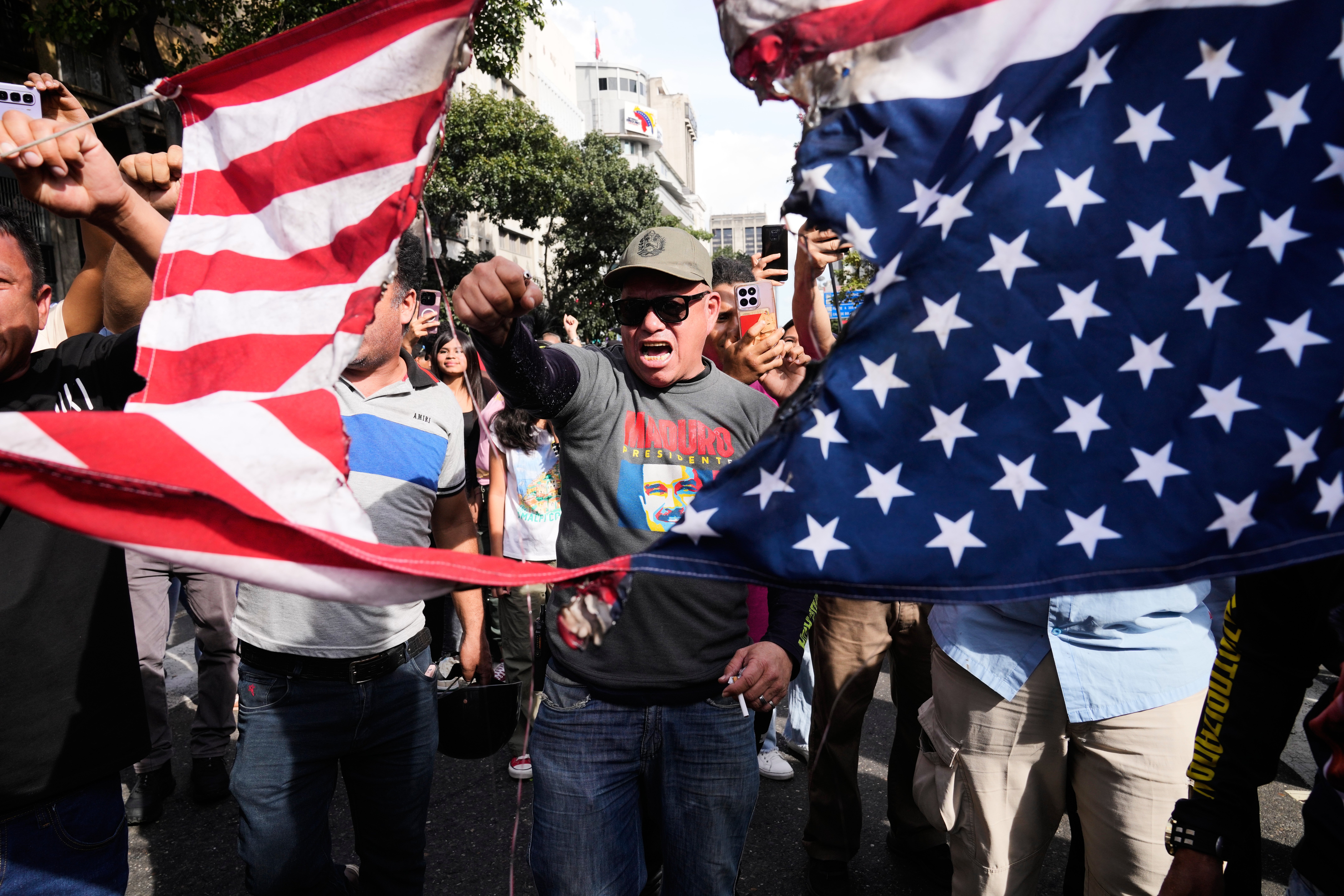 Venezuelans rip an American flag in half during a protest in Caracas against the capture of president Nicolás Maduro and his wife Cilia Flores by US military forces