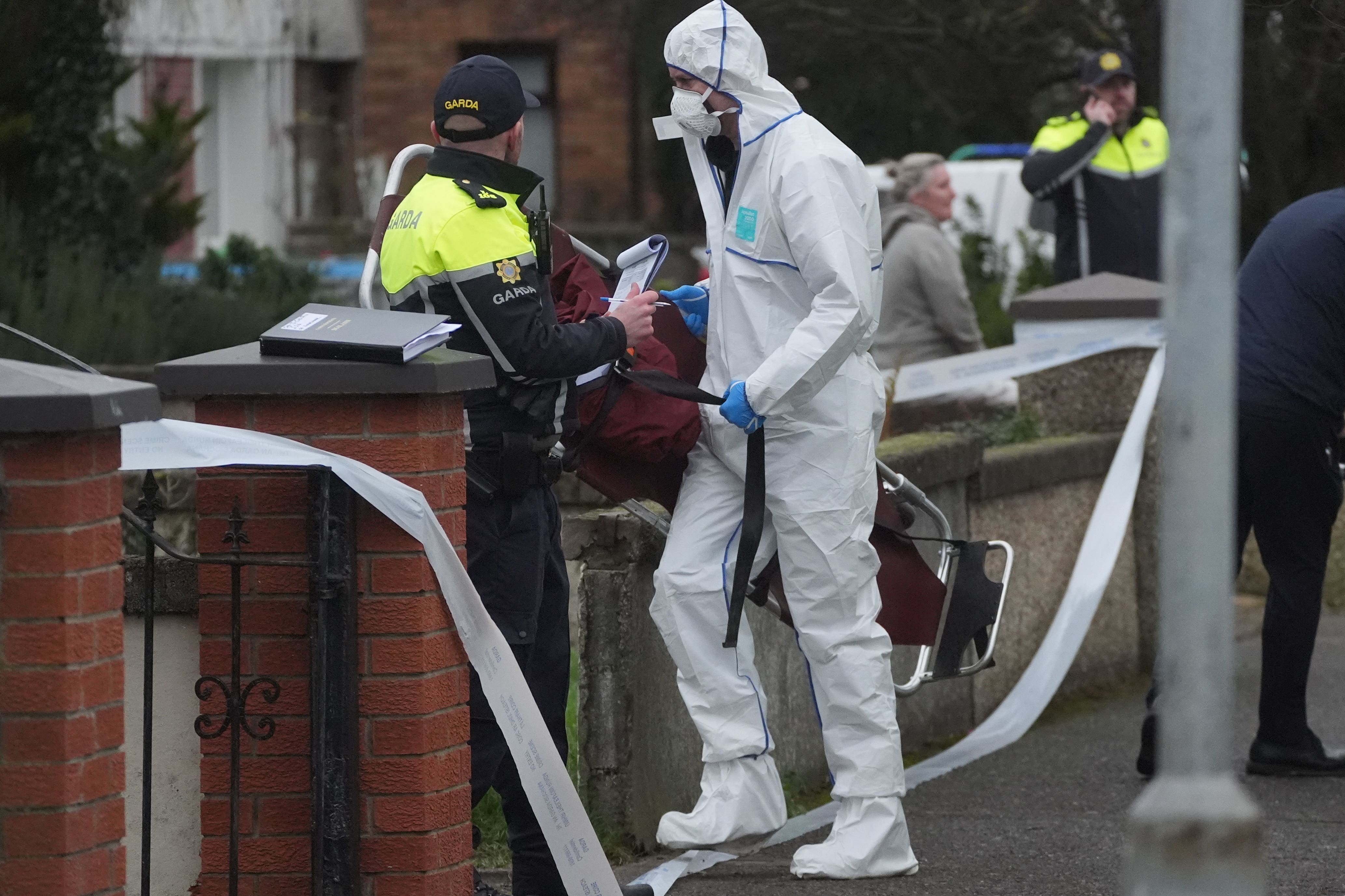 A member of An Garda Technical Bureau carries a stretcher in to a property in Clondalkin (Brian Lawless/PA)