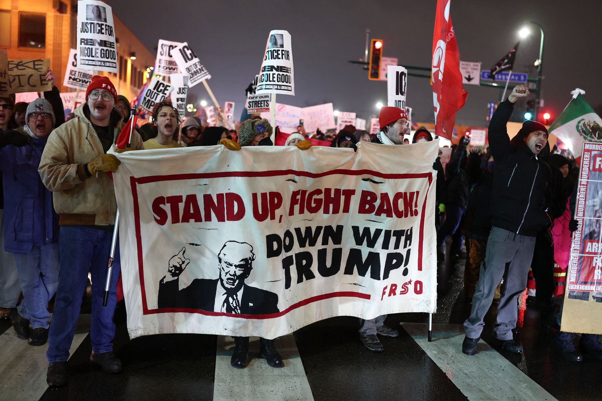 People march behind an anti-Trump banner during a ‘Stop ICE Terror’ at an emergency protest in Minneapolis Thursday