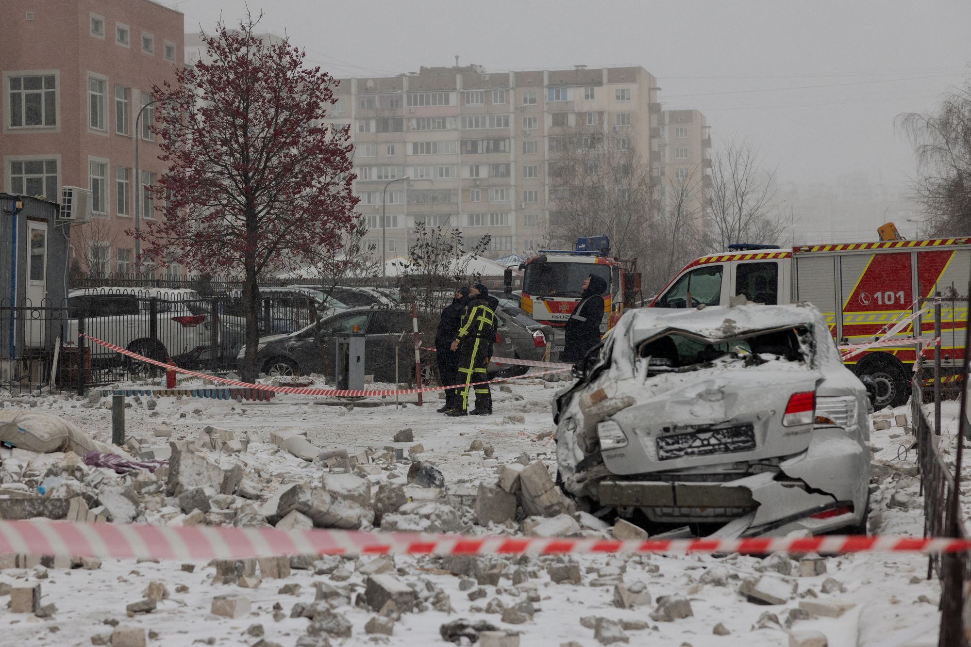 Police officers look at a damaged residential building next to a broken car following a Russian attack in Kyiv early on January 9, 2026, amid the Russian invasion of Ukraine