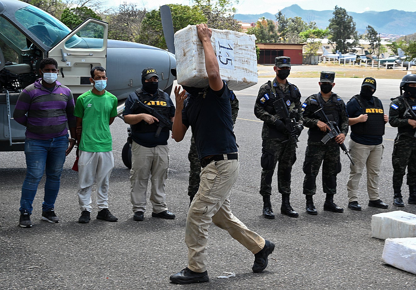 A Criminal Investigation Technical Agency (ATIC) agent carries a package with of cocaine next to two of the five Venezuelan and Colombian alleged drug traffickers from whom it was seized