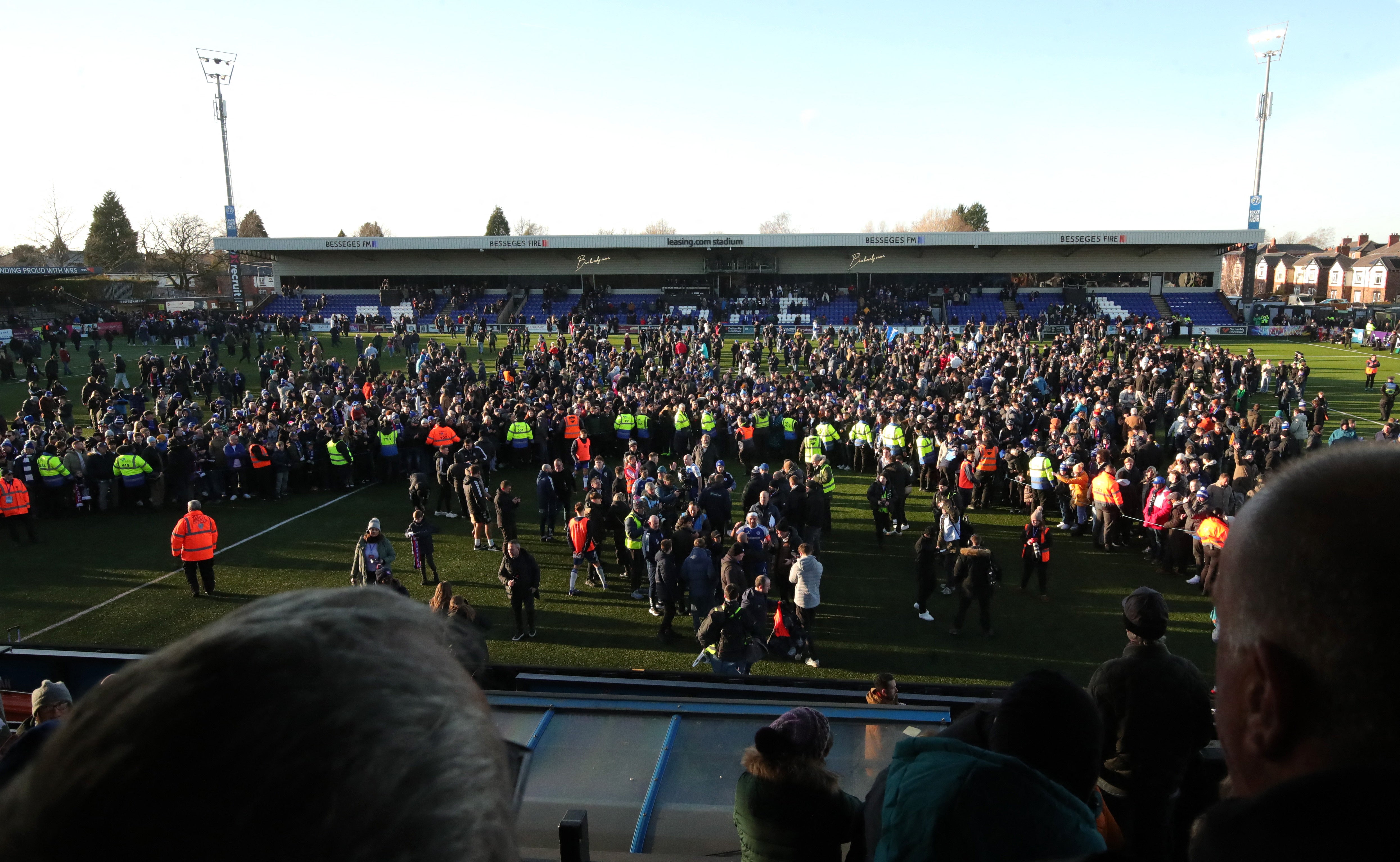 Macclesfield F.C.'s fans and players celebrate on the pitch after the match
