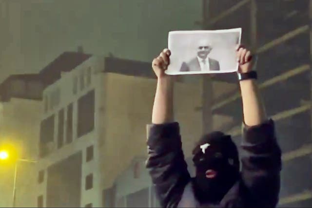 <p>A masked demonstrator holds a picture of Iran's Crown Prince Reza Pahlavi during a protest in Tehran,</p>