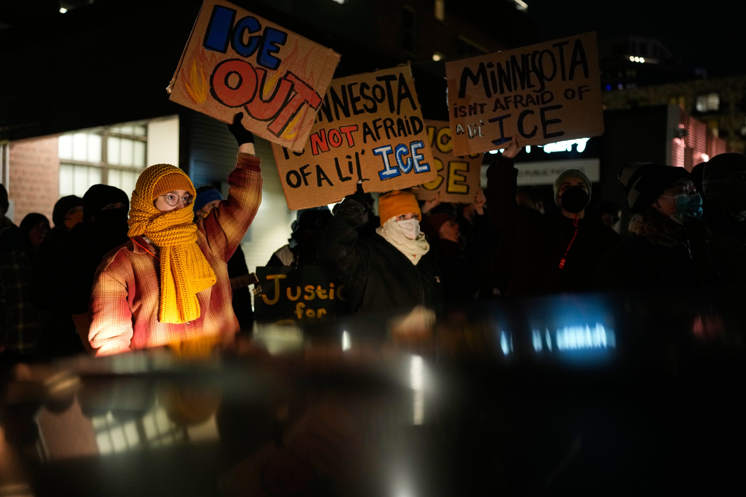 Protesters wave anti-ICE signs at a protest in downtown Minneapolis on Friday night