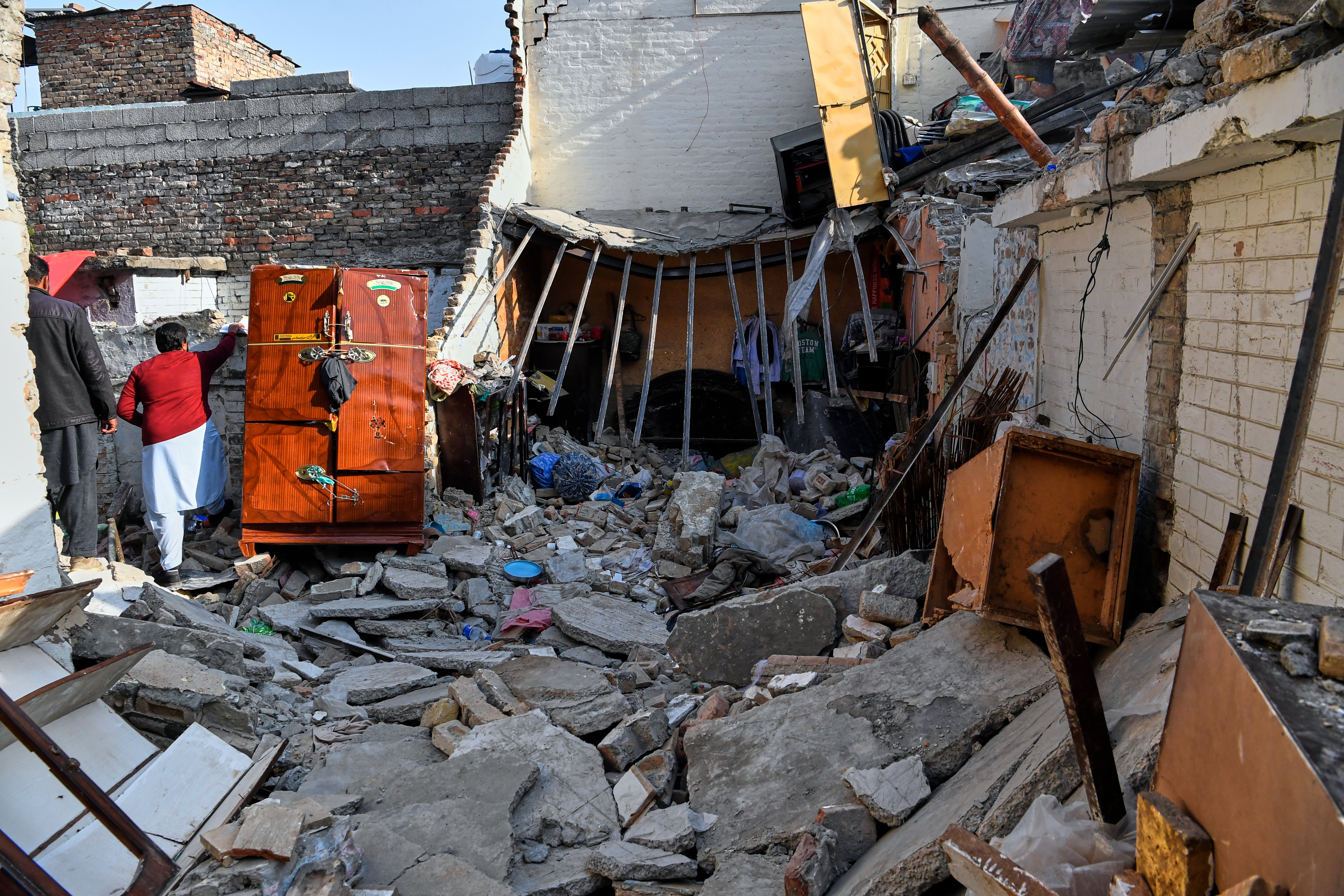 Government officials survey the damage of a home caused by a gas cylinder explosion hours after a wedding reception, in Islamabad, Pakistan, Sunday, Jan. 11, 2026. (AP Photo/Ehsan Shahzad)
