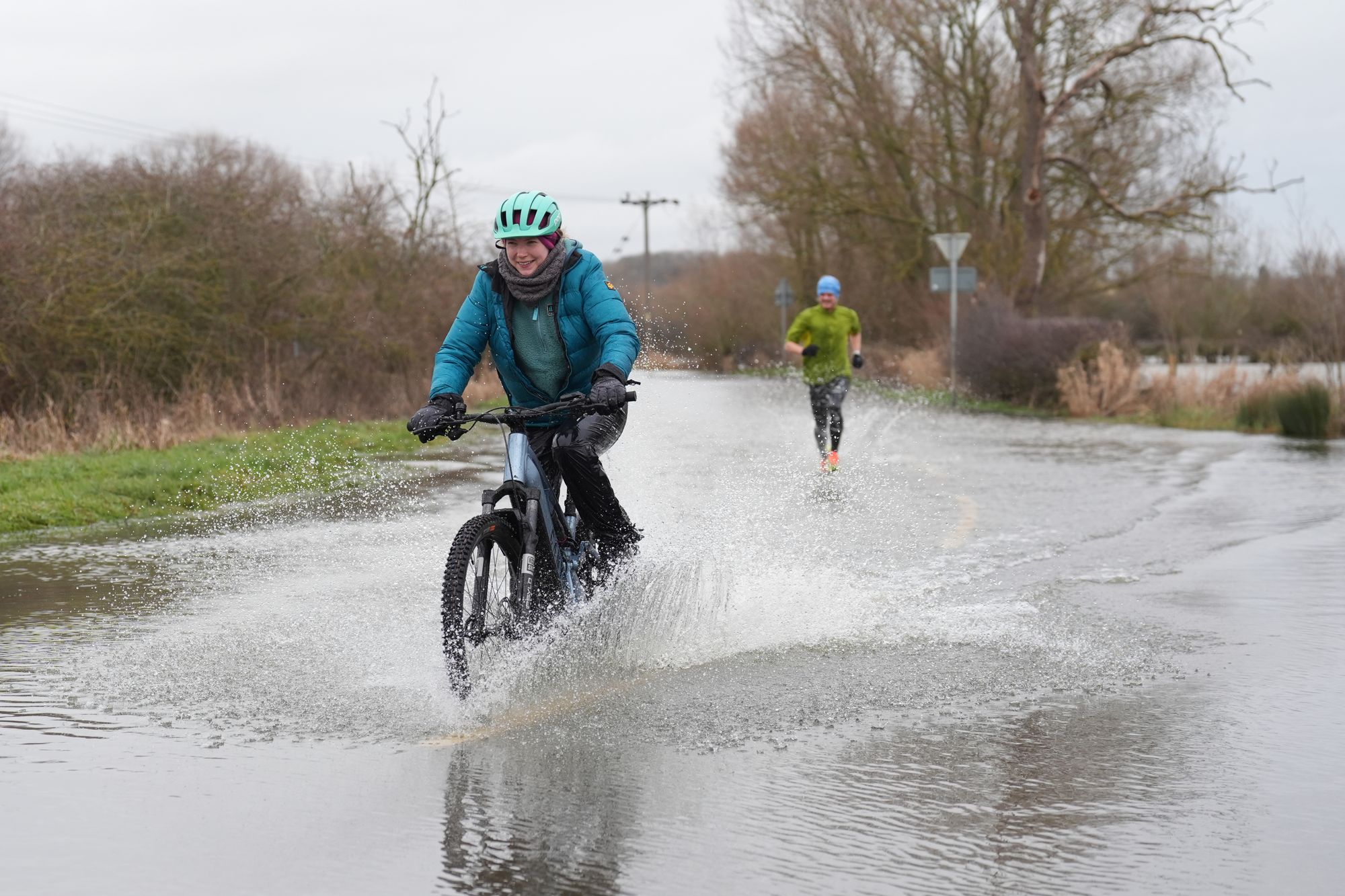 People cycle and run along a flooded road in Mountsorrel, Leicestershire, on Sunday