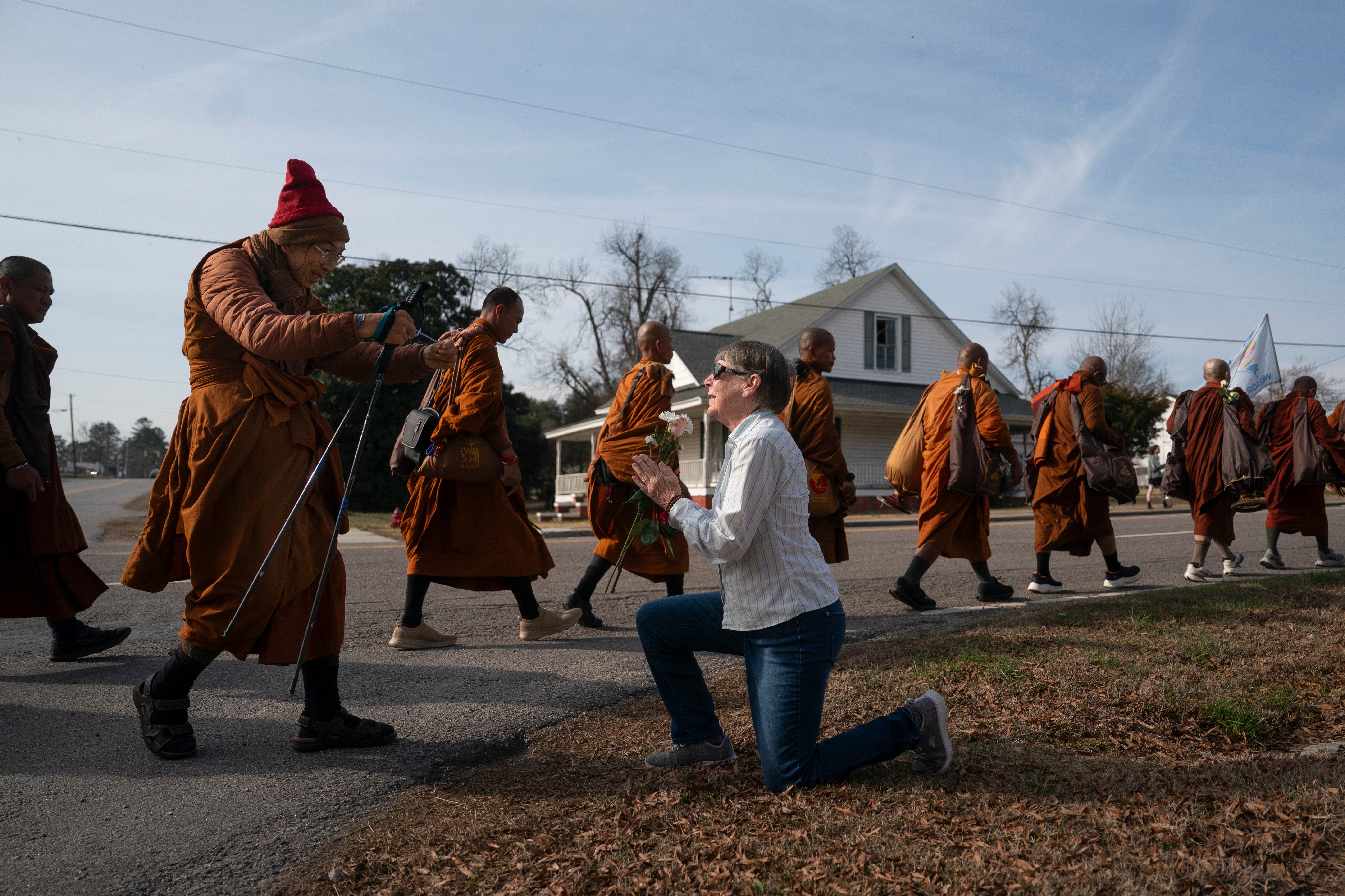 Audrie Pearce greets Buddhist monks who are participating in the, "Walk For Peace," Thursday, Jan. 8, 2026, in Saluda, S.C. (AP Photo/Allison Joyce)