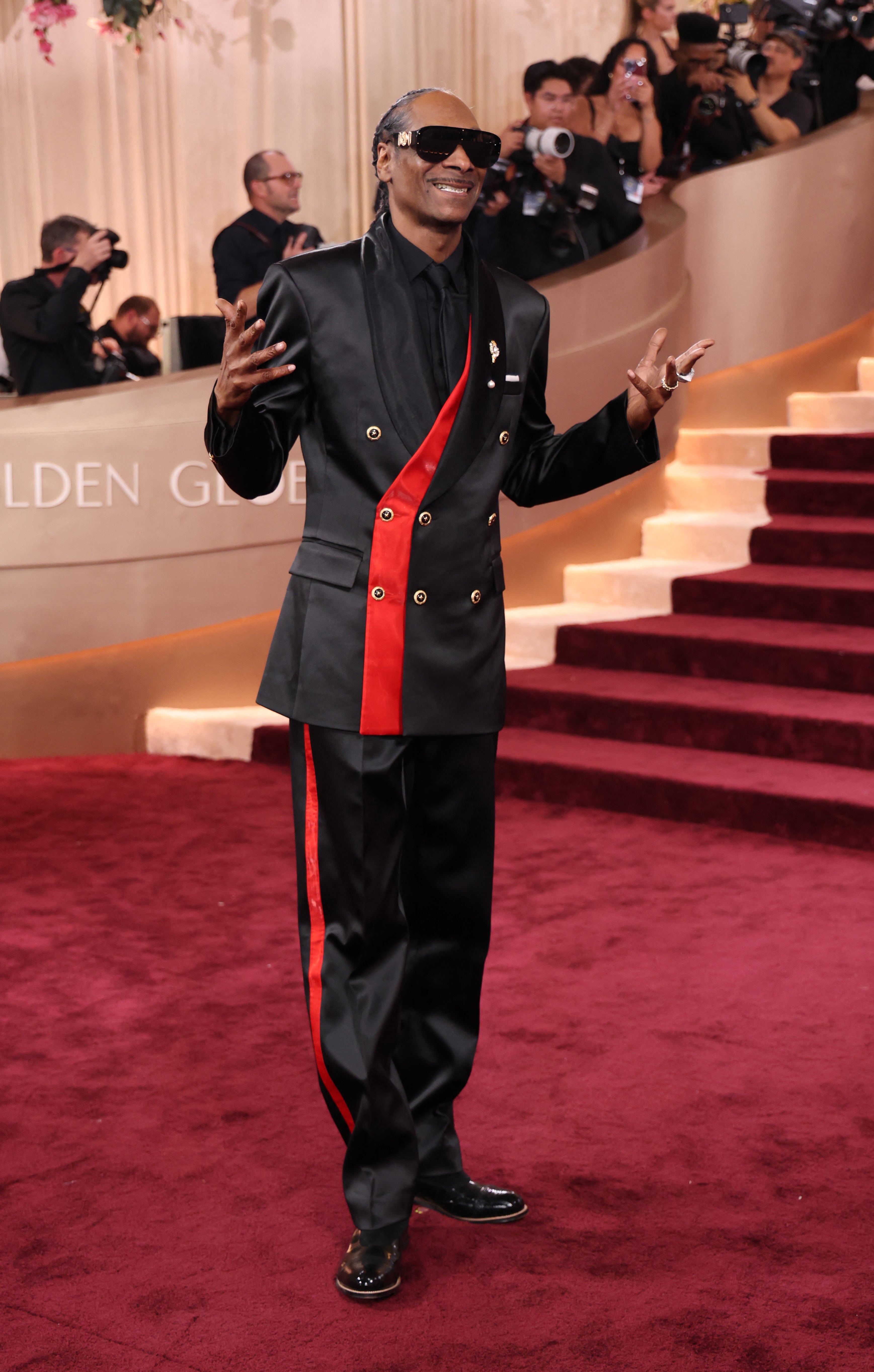 Snoop Dogg wanted more than just an evening tuxedo, opting for a black jacket with a red stripe and golden buttons, and matching pants. He completed the all-black ensemble with sunglasses and a tie