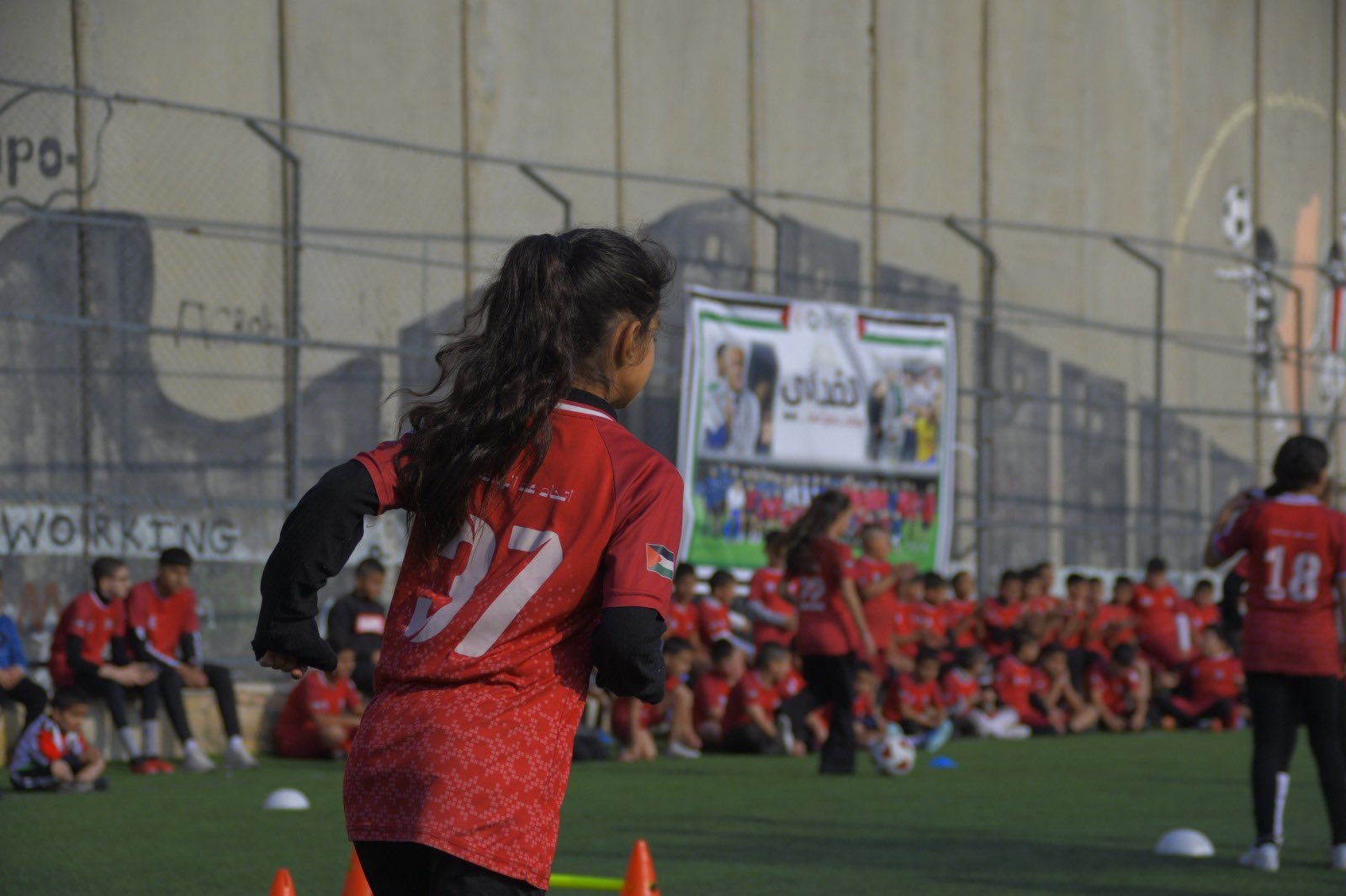 <p>A young girl plays football on Aida refugee camp’s football field in Bethlehem</p>