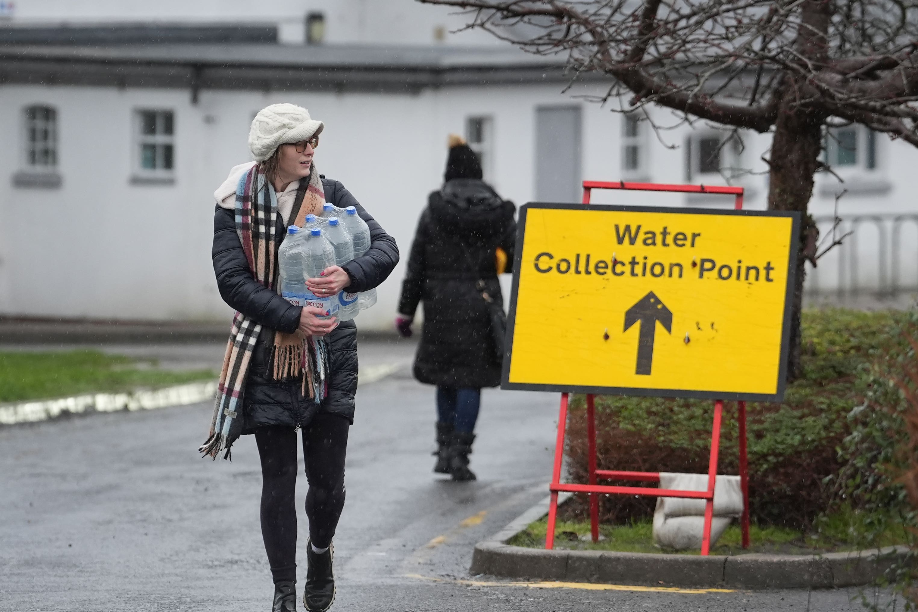 People collect water from a collection point during water outages (Gareth Fuller/PA)