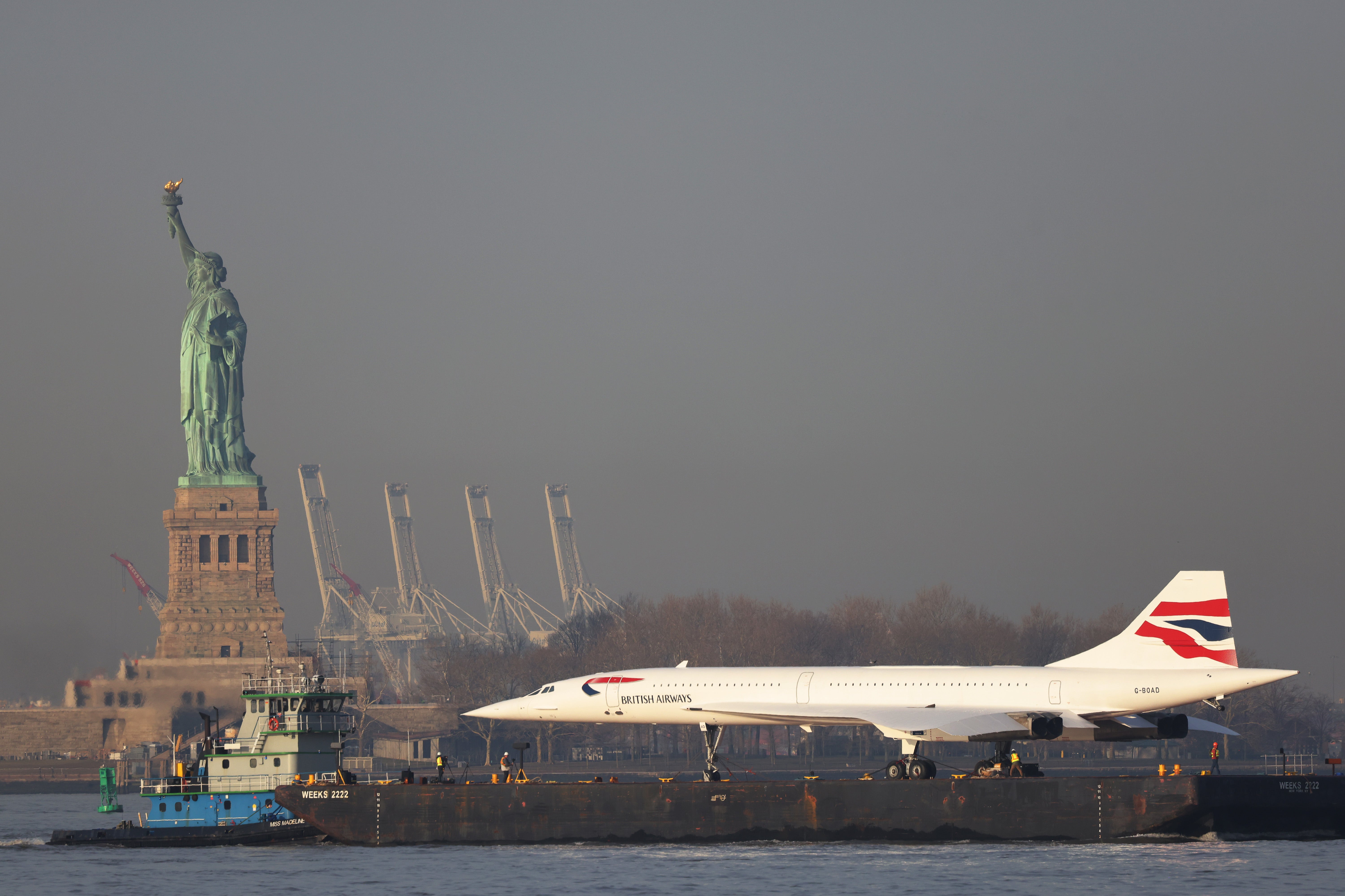 Grounded: A retired British Airways Concorde being moved by a barge past the Statue of Liberty in New York City in 2024