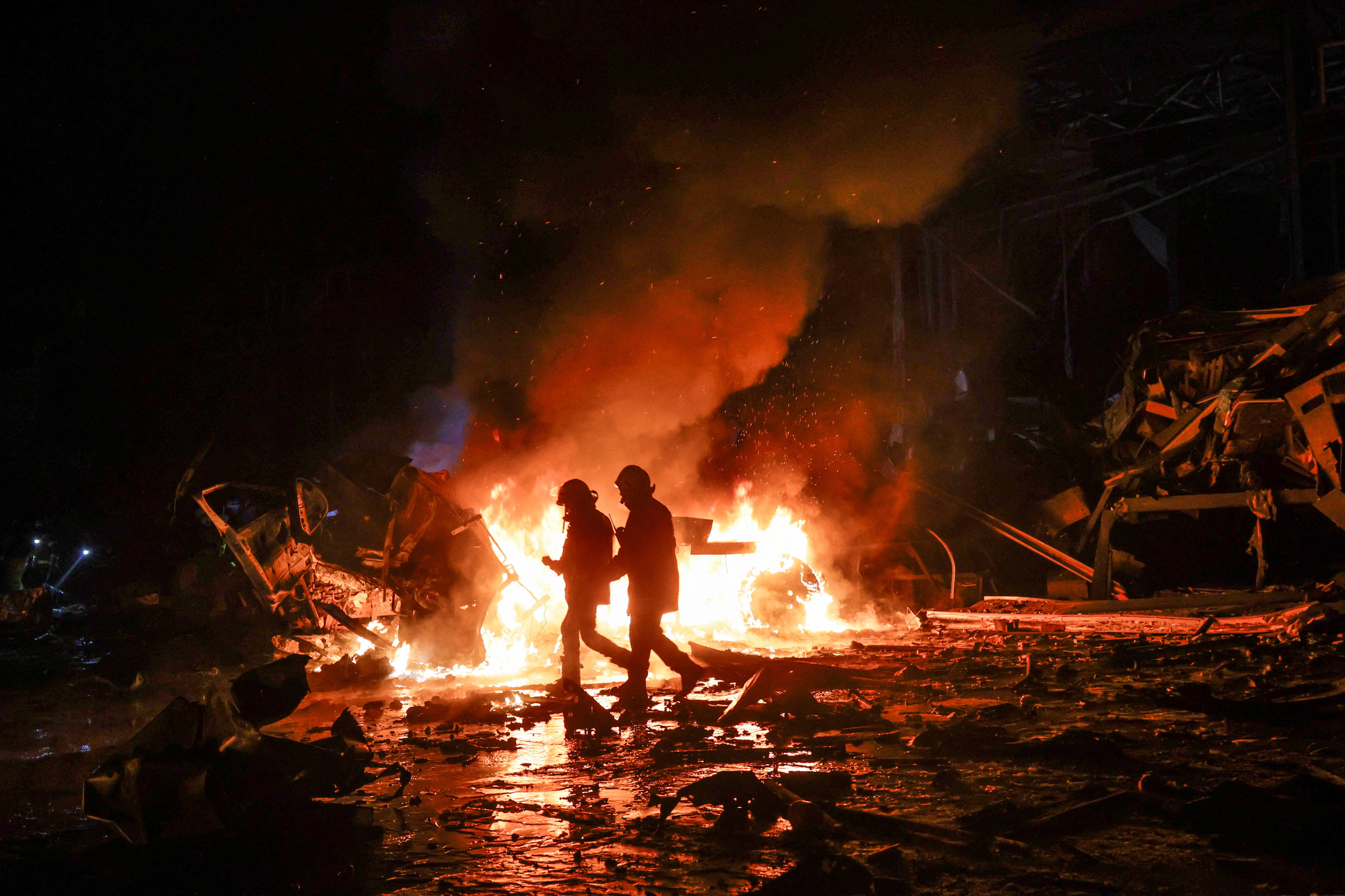 <p>Firefighters work at the site of a logistics hub of a private delivery company hit by a Russian missile strike in Kharkiv</p>