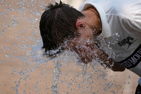 <p>A person cools himself with water from a fountain during a heatwave in Russia</p>