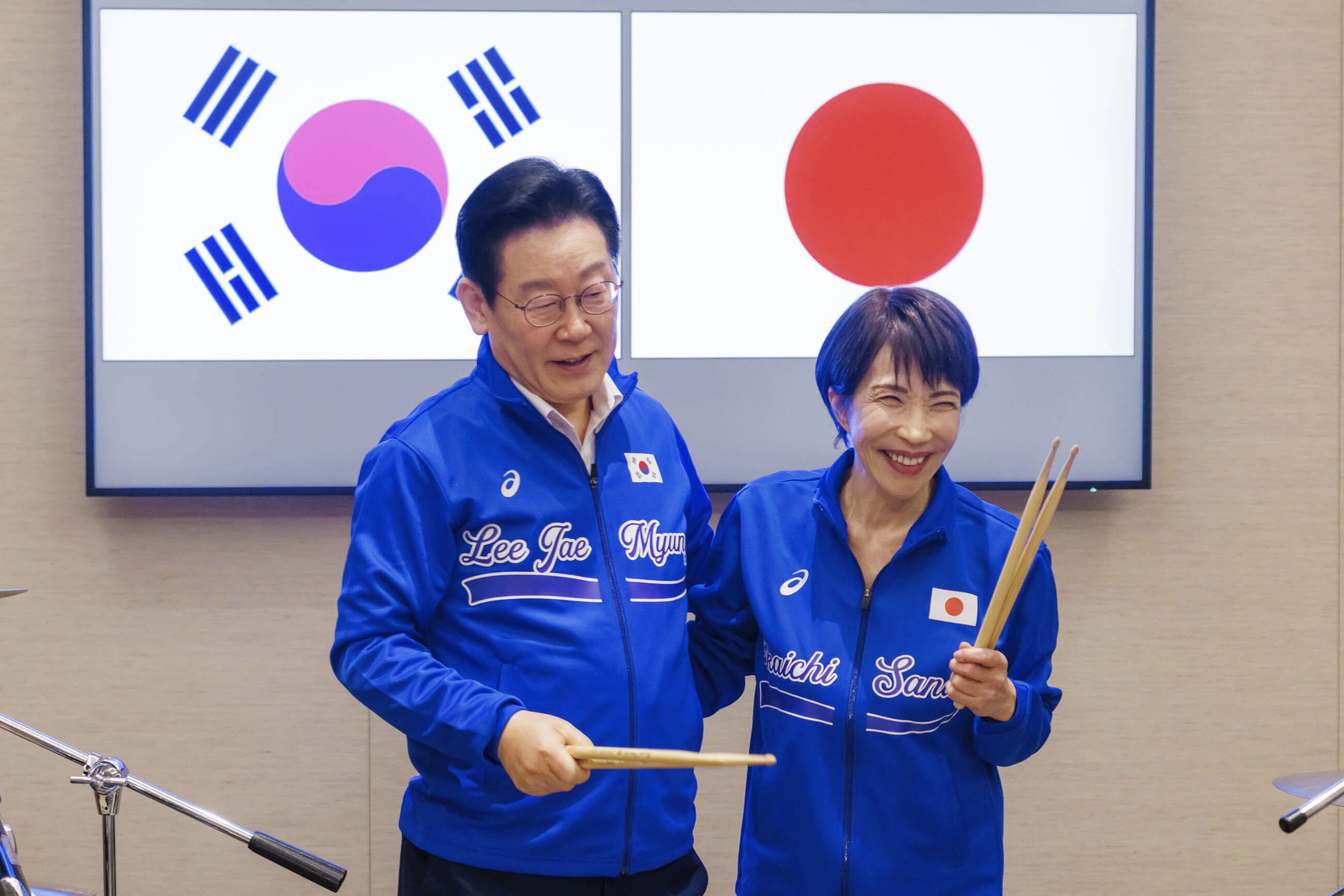 Japanese Prime Minister Sanae Takaichi, right, and South Korean President Lee Jae Myung react as they play drums together after their talks in Nara