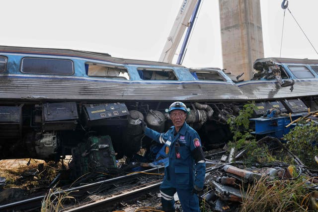 <p>A rescuer stands near the wreckage after a construction crane fell into a passenger train in Nakhon Ratchasima province, Thailand.</p>