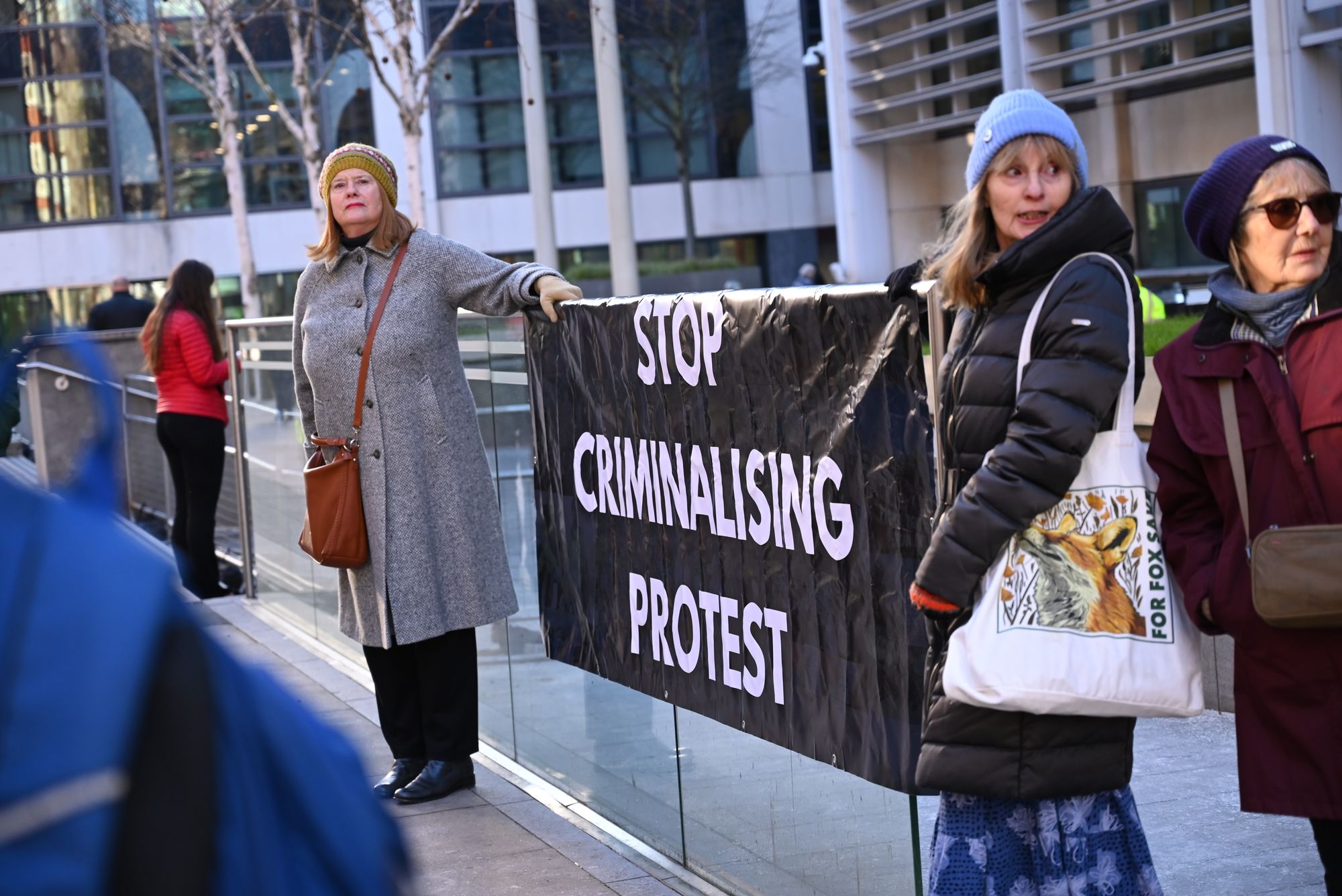 <p>Two women holding banner reading ‘Stop criminalising protest’</p>