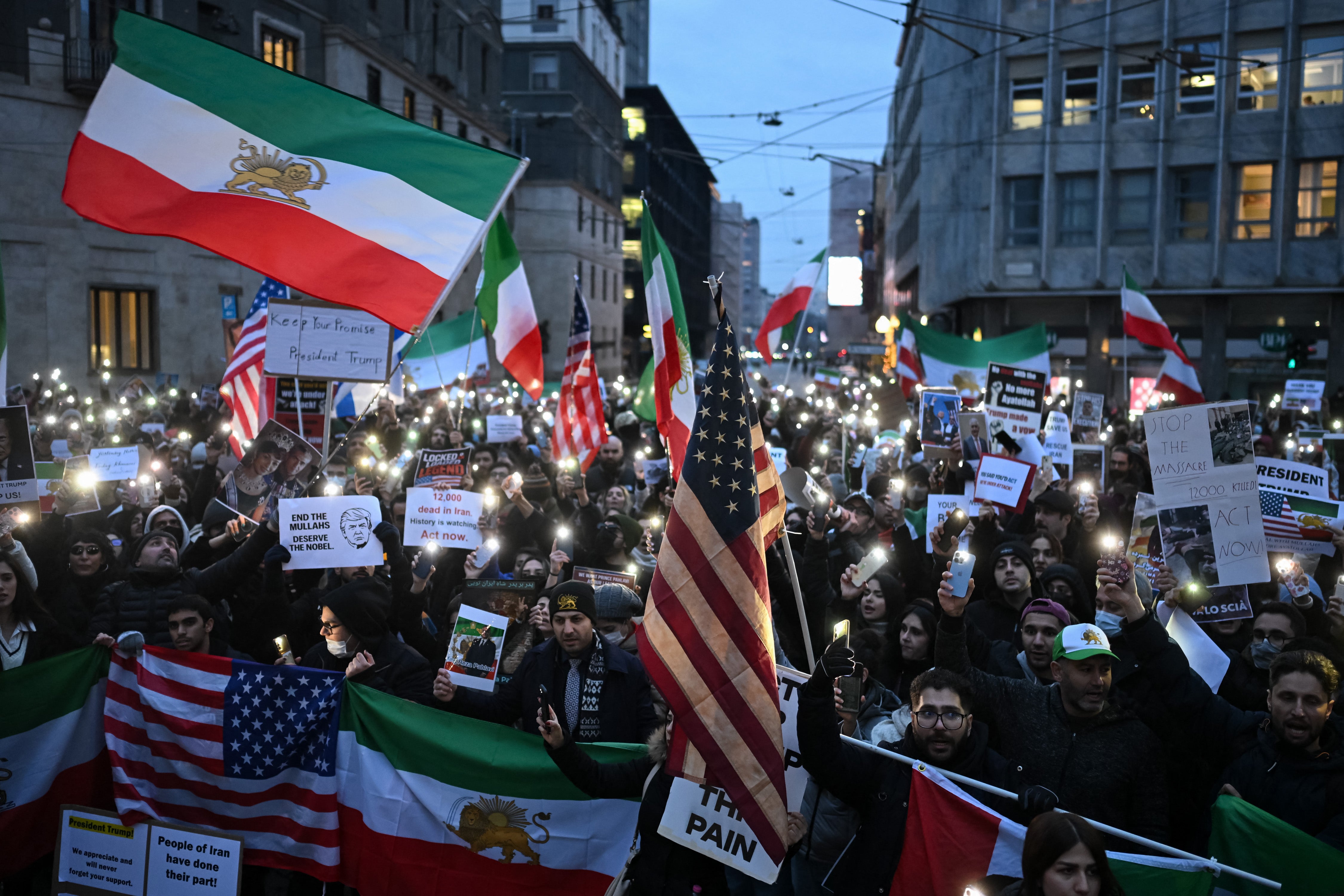 Anti-Iranian regime protesters hold pre-1979 Islamic Revolution Iranian flags, US flags and light their cellphones during a gathering outside the US Consulate in Milan, on 13 January 2026