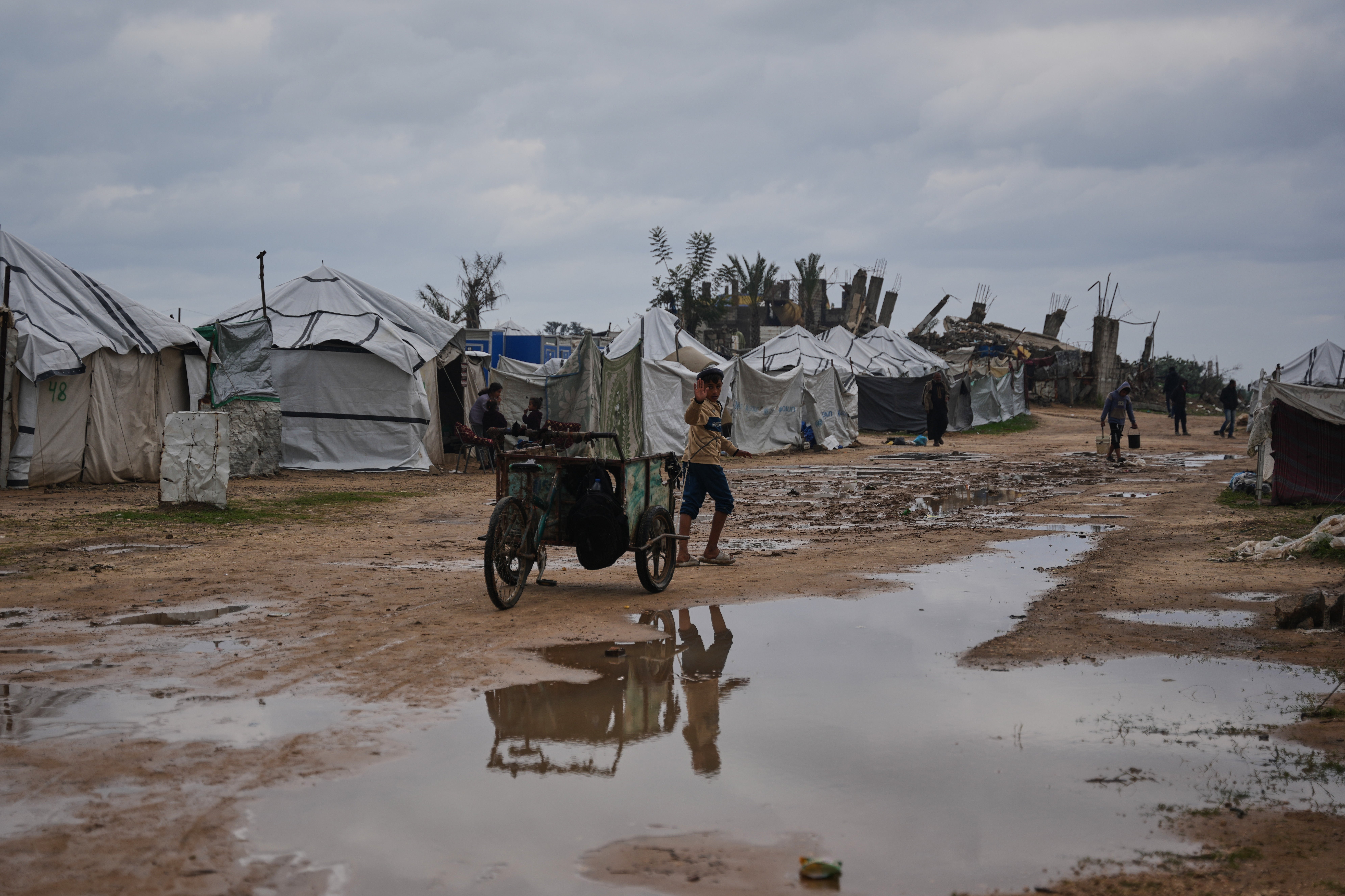 A child walks in a tent camp for displaced Palestinians after heavy rain in Nuseirat, Gaza