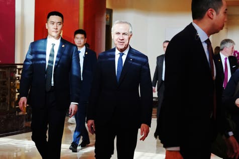 <p>Mark Carney walks through the lobby of a hotel in Beijing</p>