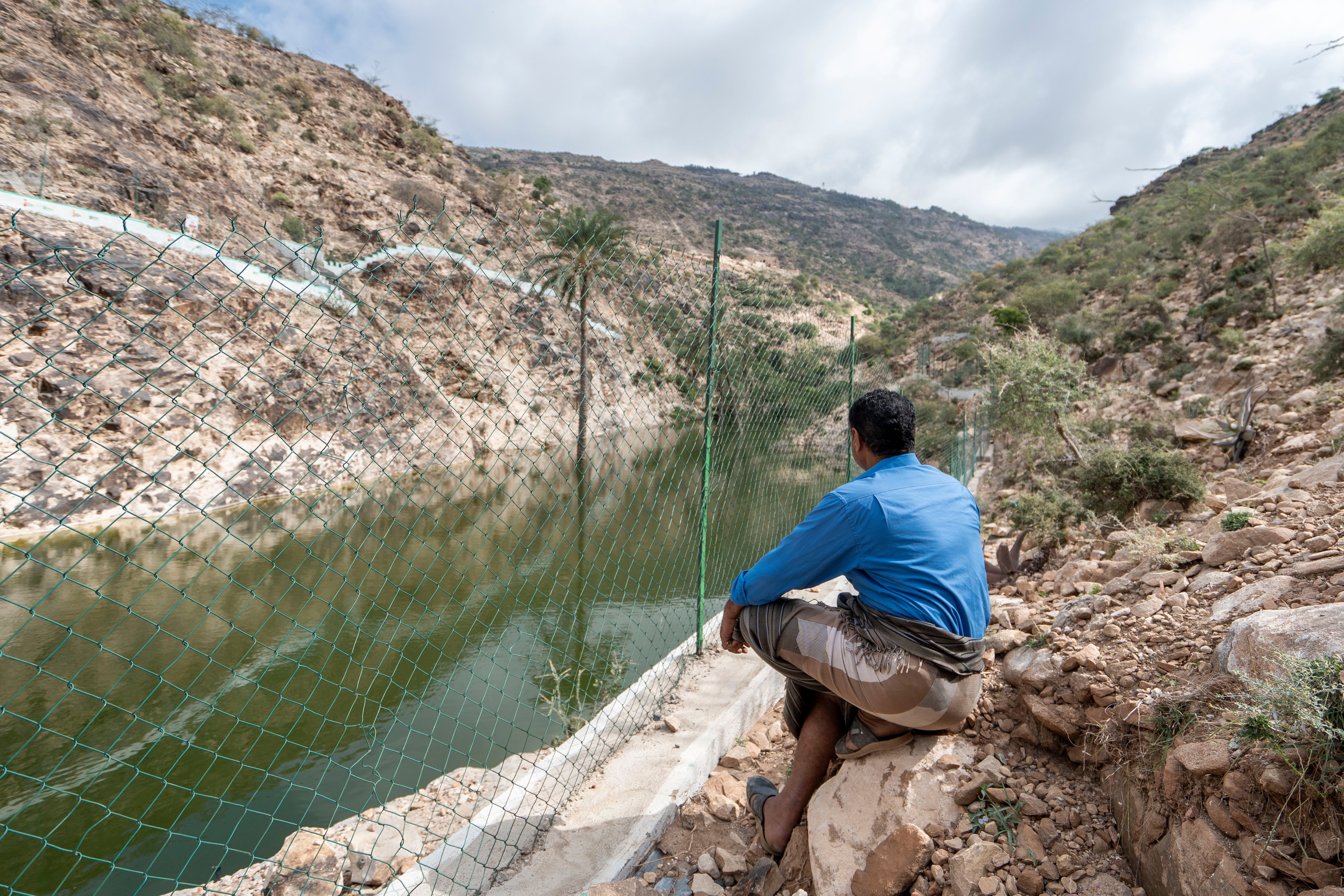 <p>Mujib Mohammed Ali looks across the rehabilitated water channel that lies next to his farm in the Taiz governorate in western Yemen</p>