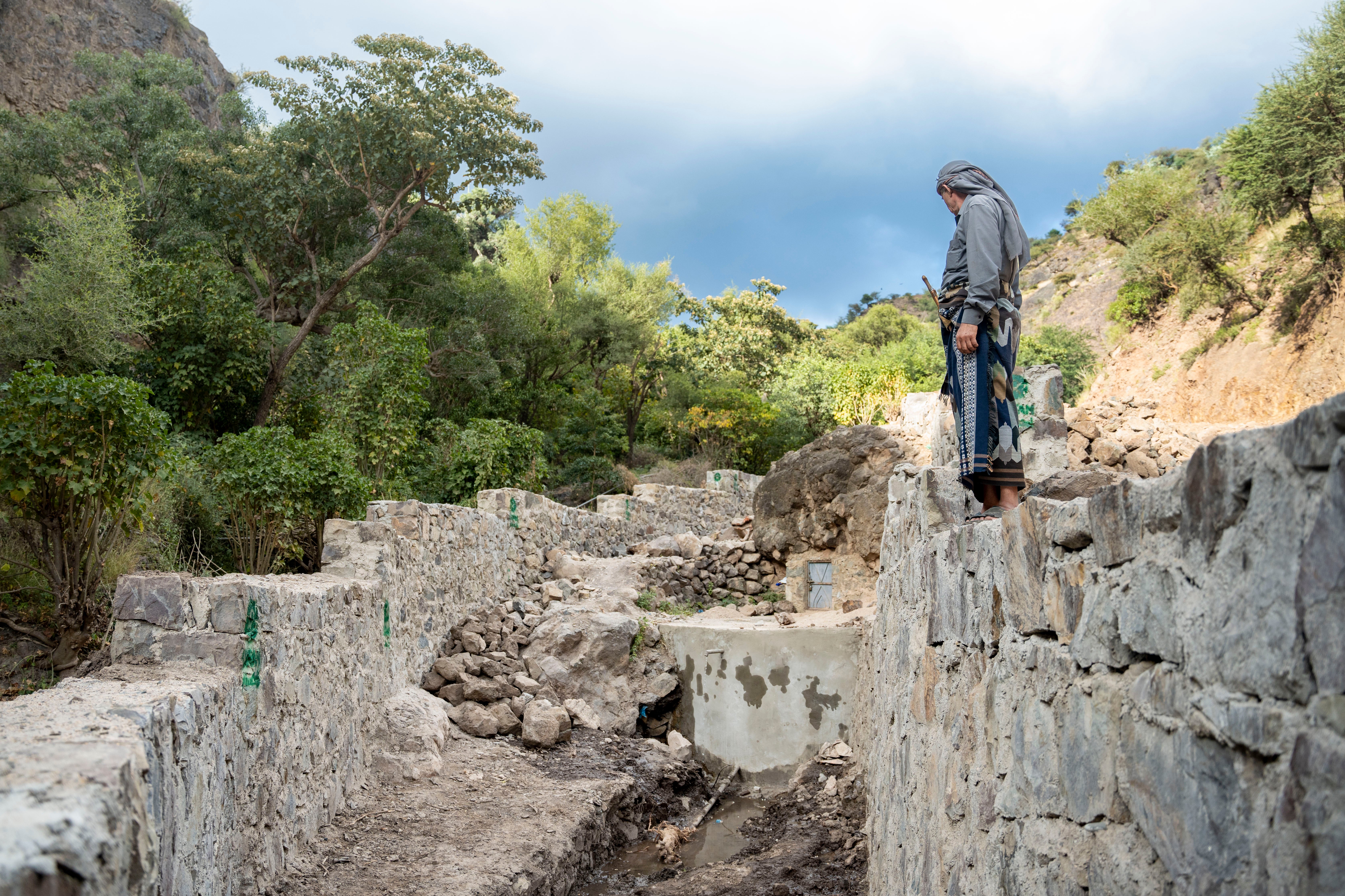 Jameel Mahyoub Saif, 55, is pictured next to water infrastructure that has been rehabilitated with concrete in his village