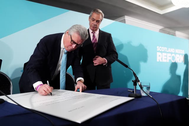Malcolm Offord, left, signs his house of lords retirement letter with Reform UK leader Nigel Farage looking on (Andrew Milligan/PA)