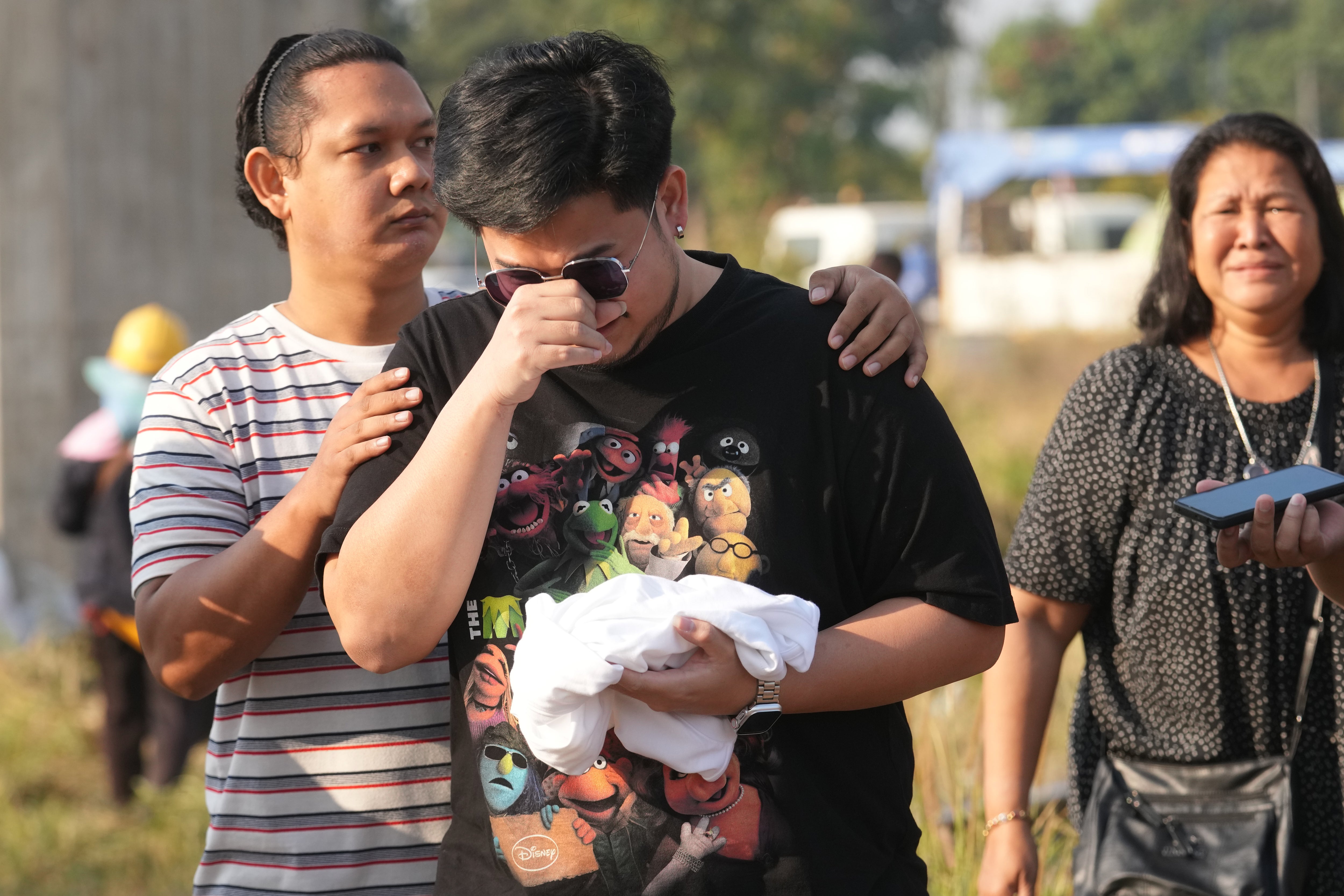 Relatives of the victims react near the site where a construction crane fell into a passenger train on Wednesday, in Nakhon Ratchasima province