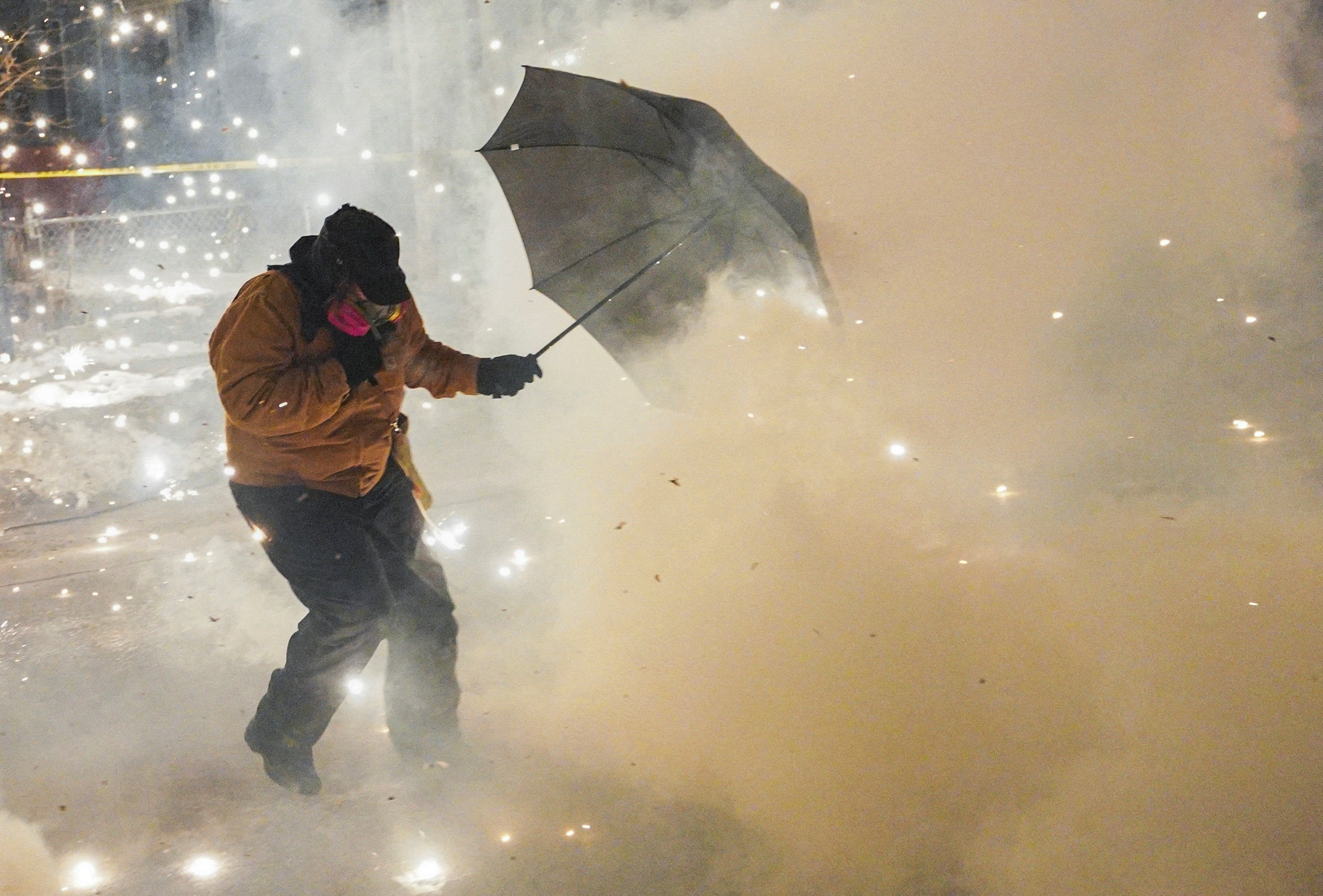 A protesting community member attempts to protect themselves as federal agents fire munitions and pepper balls, as tensions rise after federal law enforcement agents were involved in a shooting incident, a week after a U.S. Immigration and Customs Enforcement (ICE) agent fatally shot Renee Nicole Good, in north Minneapolis, Minnesota, U.S., January 14, 2026. REUTERS/Ryan Murphy