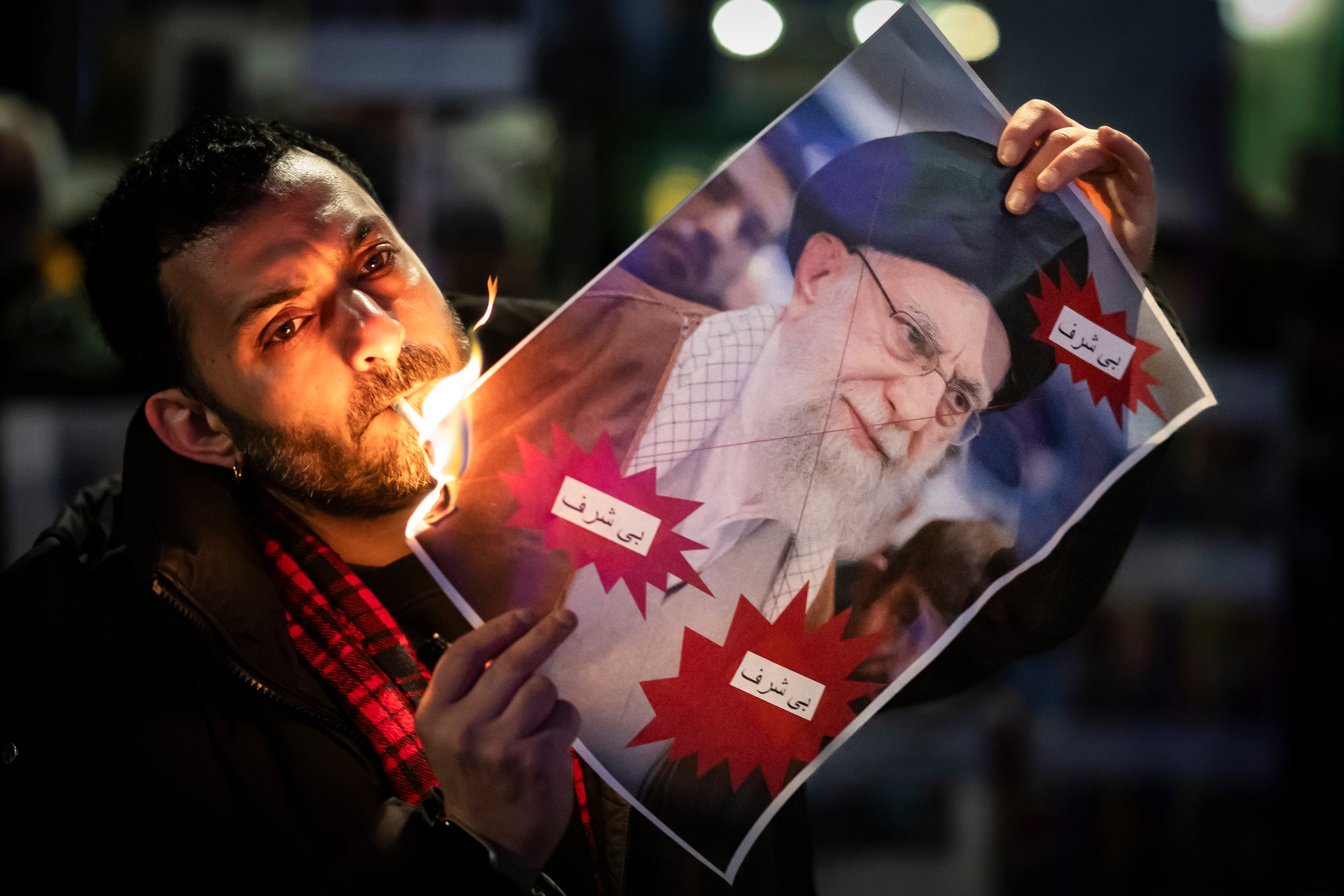 A protester burns an image of the Ayatollah Ali Khamenei with a cigarette during rally in support of the nationwide mass demonstrations in Iran against the government, Tuesday, Jan. 13, 2026 in Zuerich, Switzerland.(Michael Buholzer /Keystone via AP)