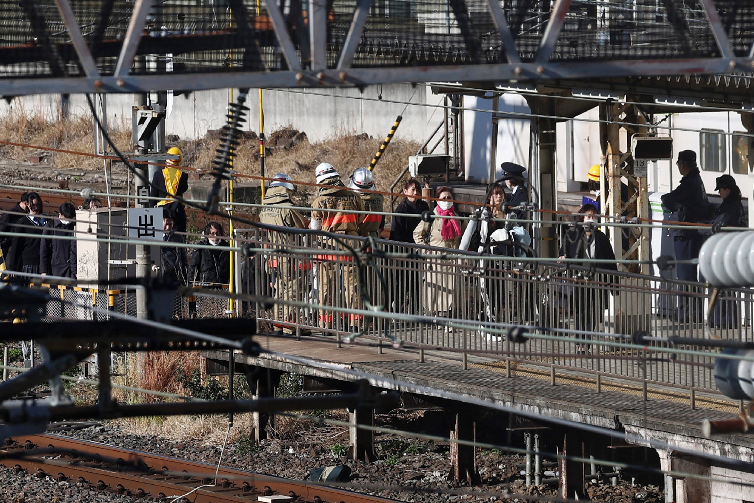 Commuters walk along tracks towards the Tamachi station after a power outage halted services in Tokyo