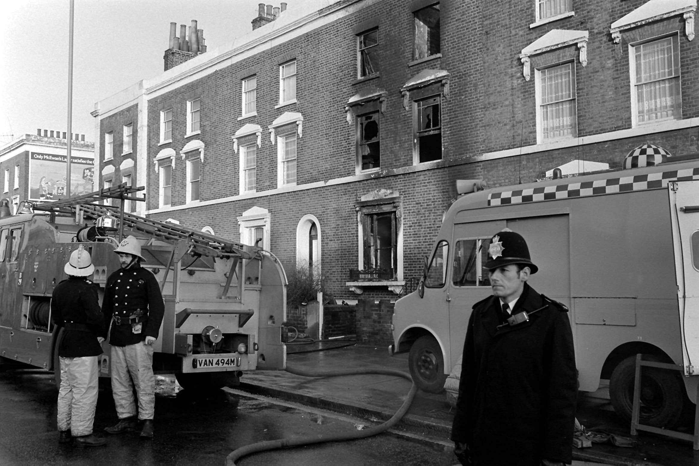 Firemen and police in front of the flame-ravaged house in New Cross Road (PA)