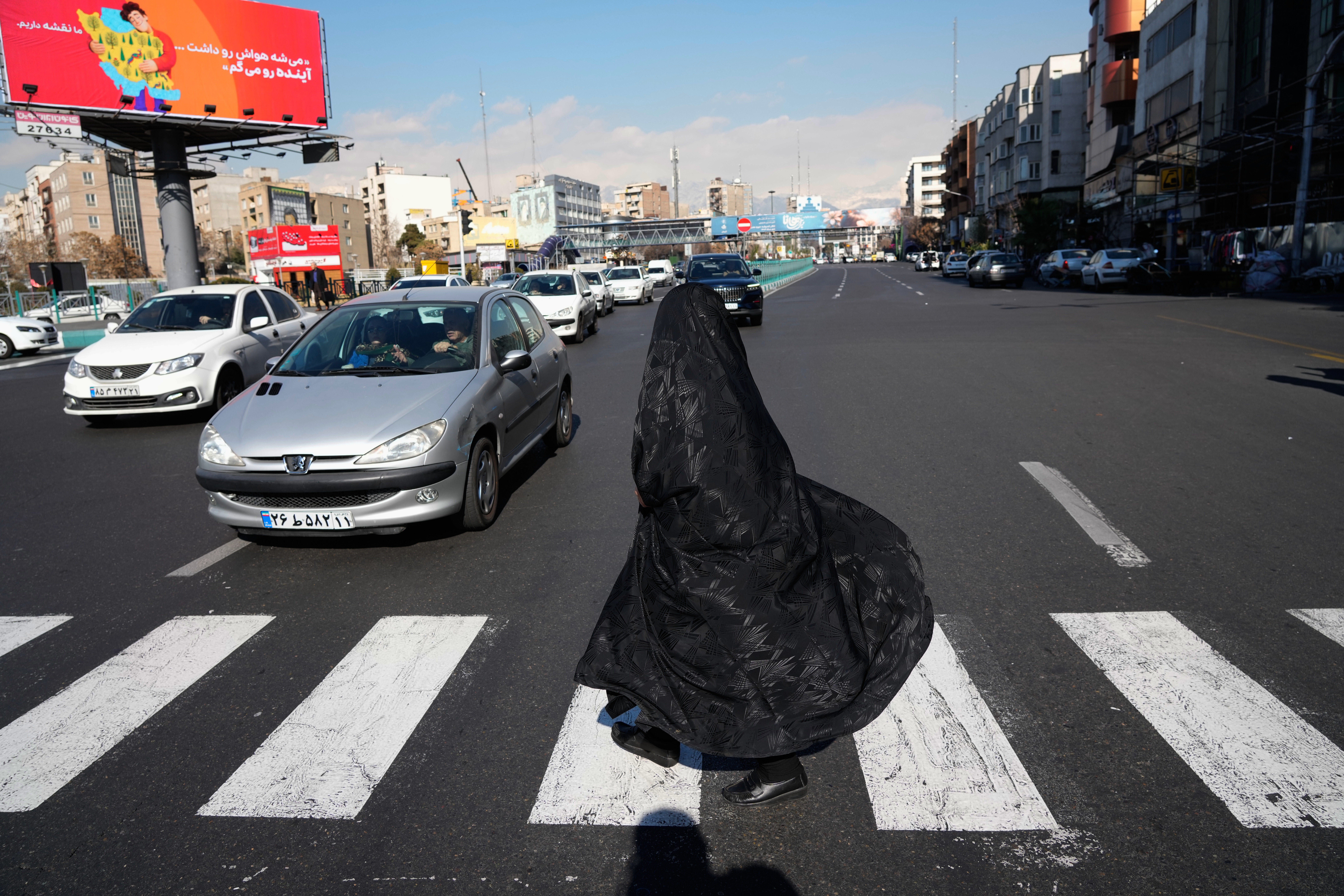 A woman crosses an intersection in downtown Tehran, Iran, Friday, Jan. 16, 2026. (AP Photo/Vahid Salemi)