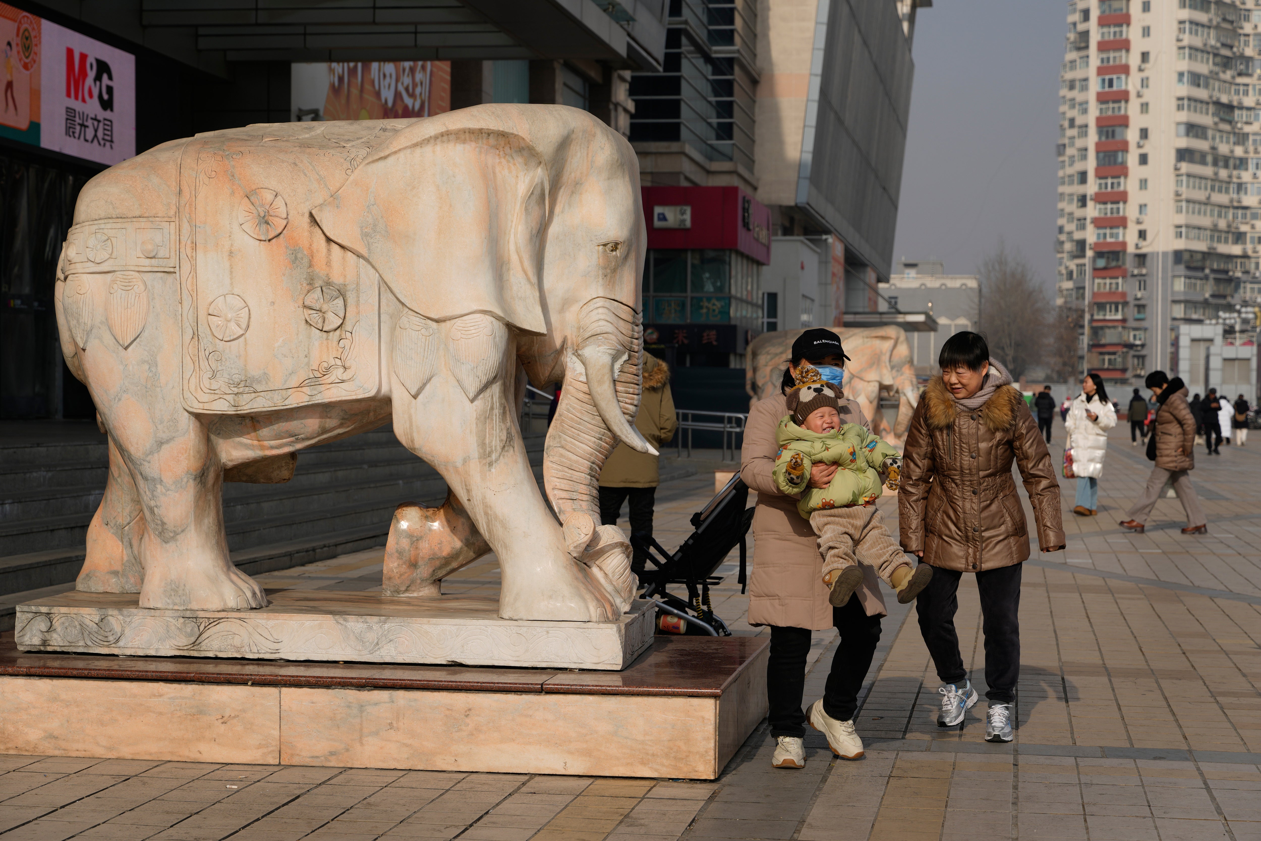 A woman lifts up a child in Beijing, China, on Jan. 15, 2026. (AP Photo/Ng Han Guan)
