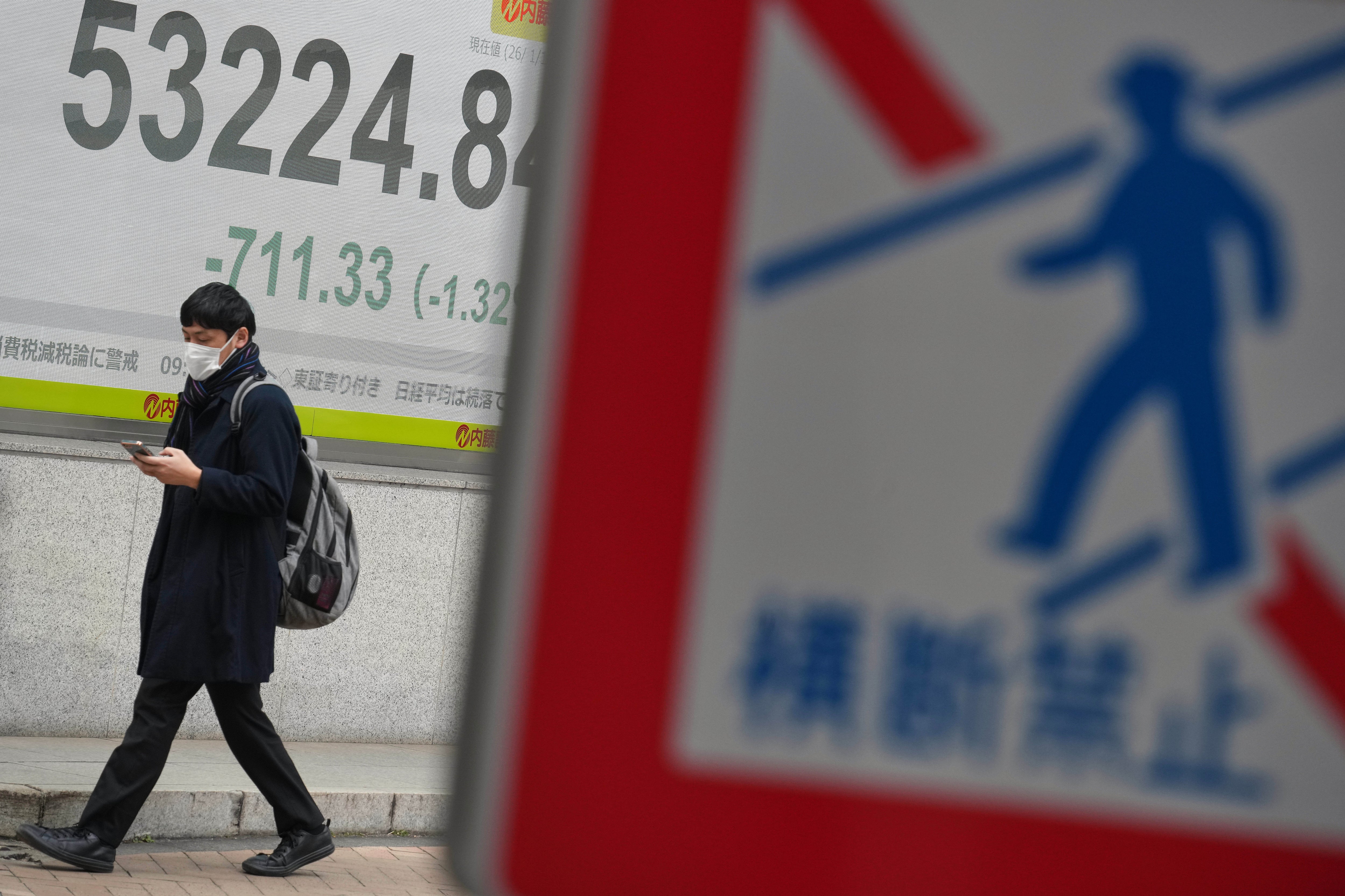 A person walks in front of an electronic stock board showing Japan's Nikkei index at a securities firm Monday, Jan. 19, 2026, in Tokyo. (AP Photo/Eugene Hoshiko)