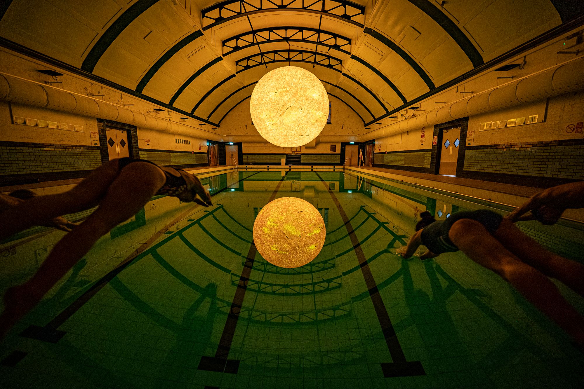 People dive into the water beneath ‘Helios’