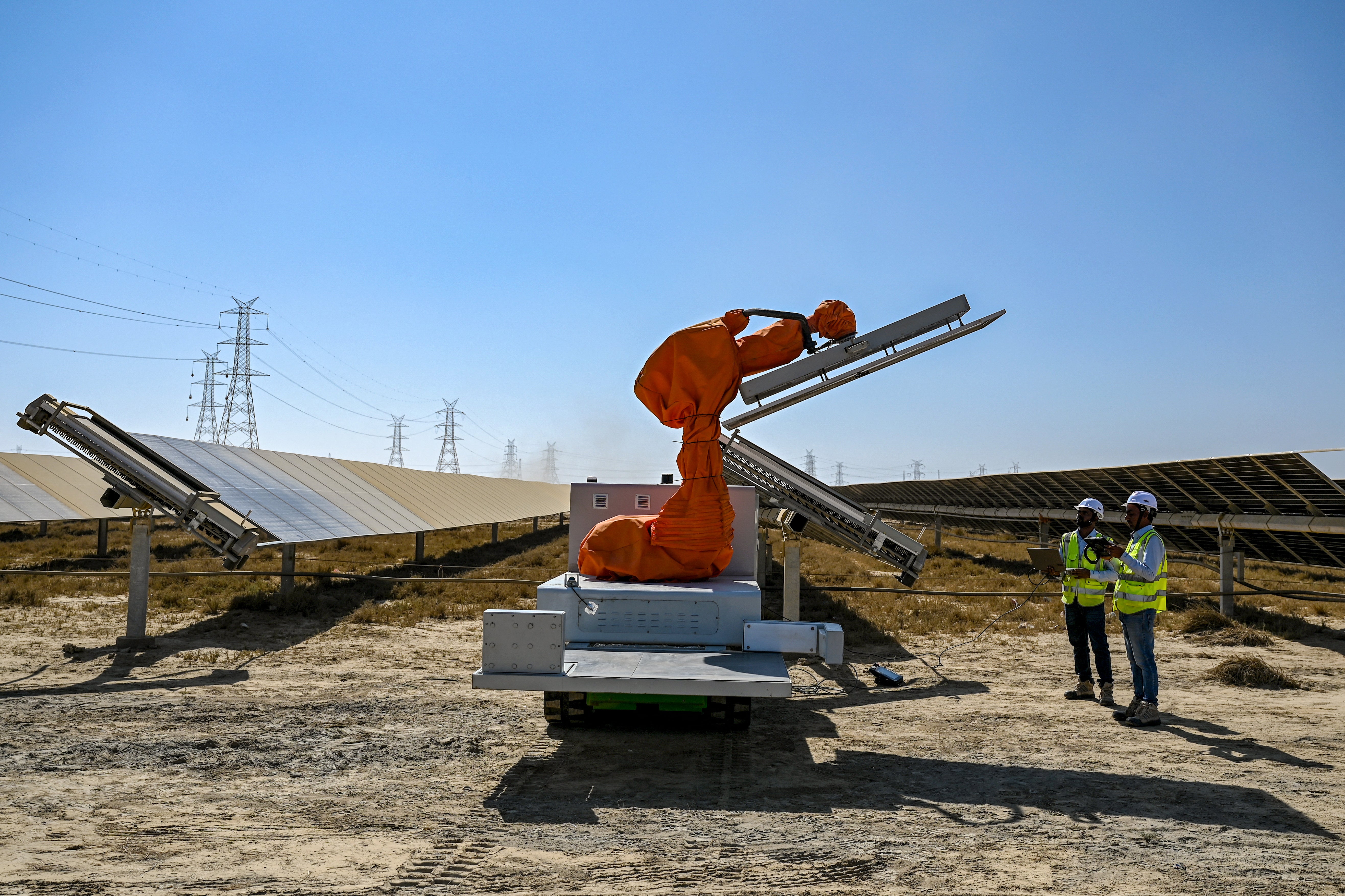 Workers operating a machine during the installation of a solar panel at the Adani Group-owned Khavda Renewable Energy Park in Khavda