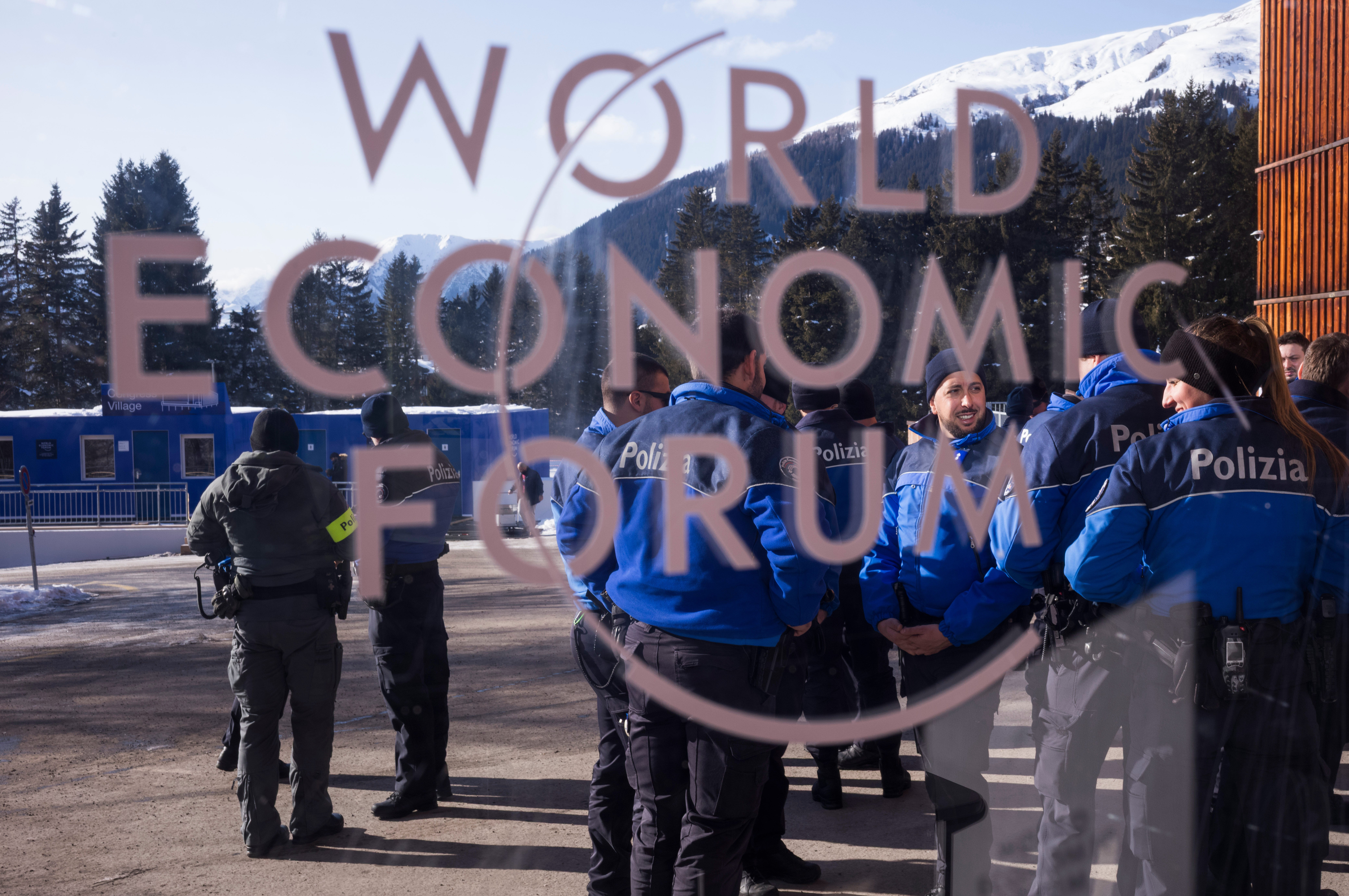 Police officers stand behind a logo of the World Economy Forum in front of the Congress Center where the Annual Meeting Forum takes place in Davos, Switzerland.
