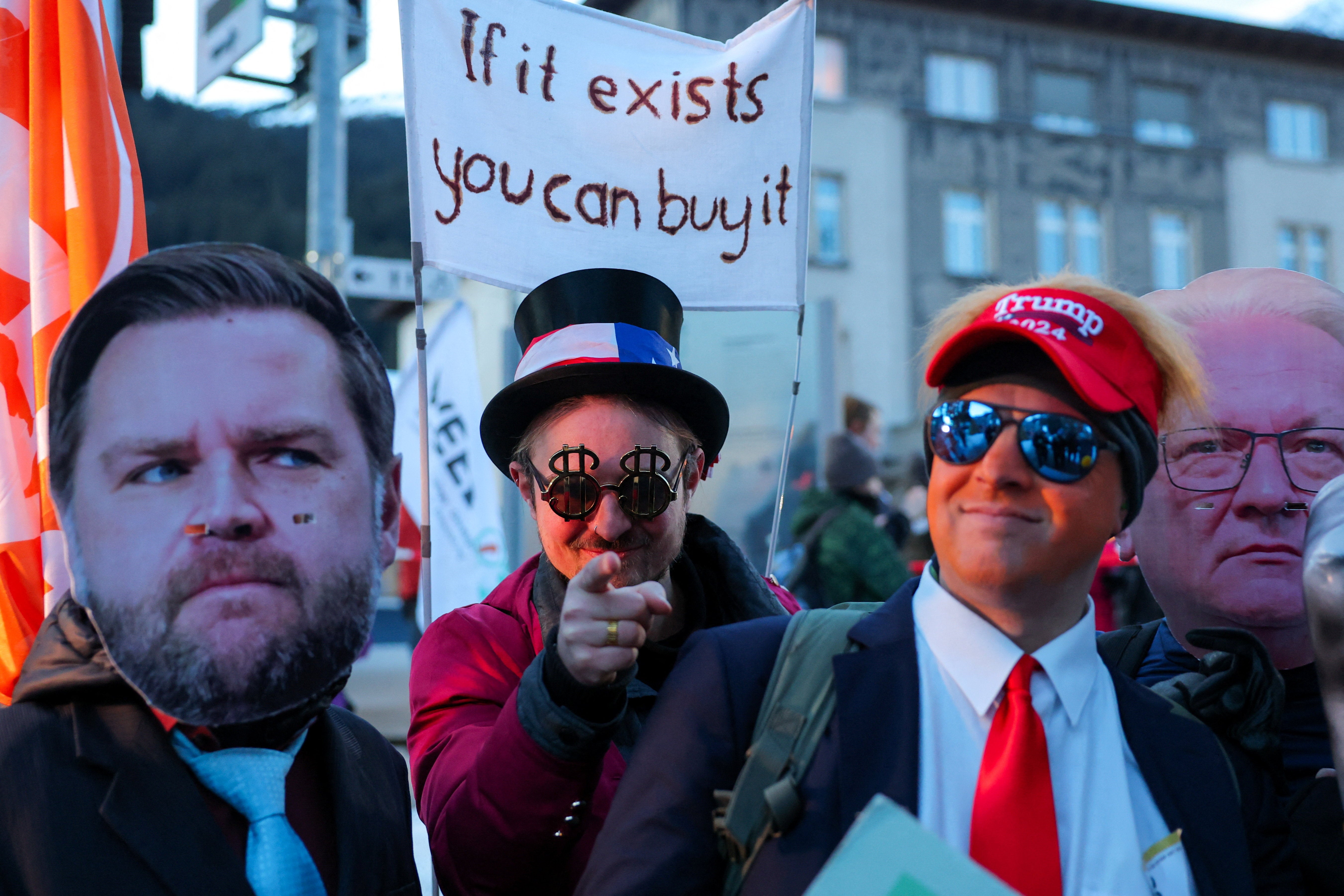 Activists wearing masks of Rheinmetall CEO Armin Papperger and U.S. Vice President JD Vance stand next to a person wearing a costume depicting U.S. President Donald Trump.