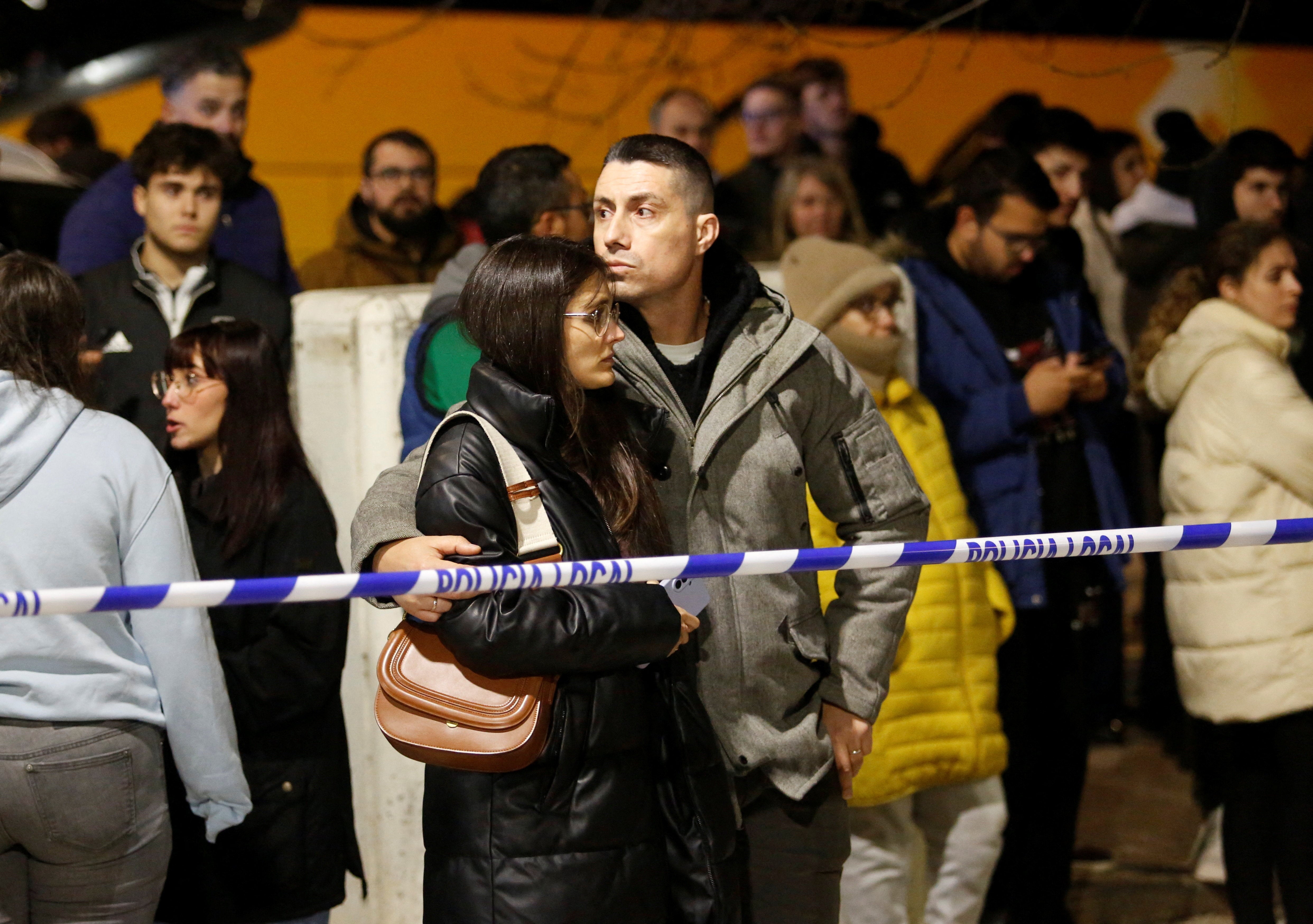 People wait behind a police cordon at the scene of the crash