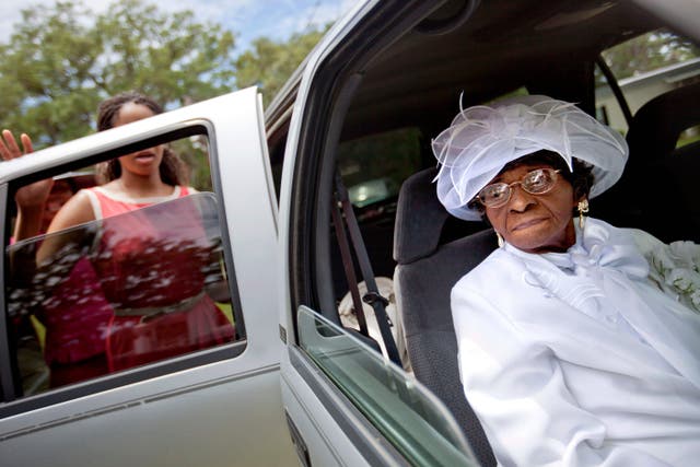 <p>Cathleen Hillary, 93, the oldest resident of Sapelo Island leaves a church service with her great granddaughter Milaika Ellison</p>