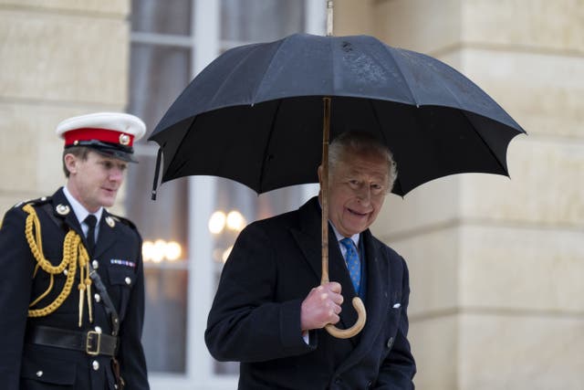 The King shelters under an umbrella as he leaves Lancaster House in central London (Aaron Chown/PA)