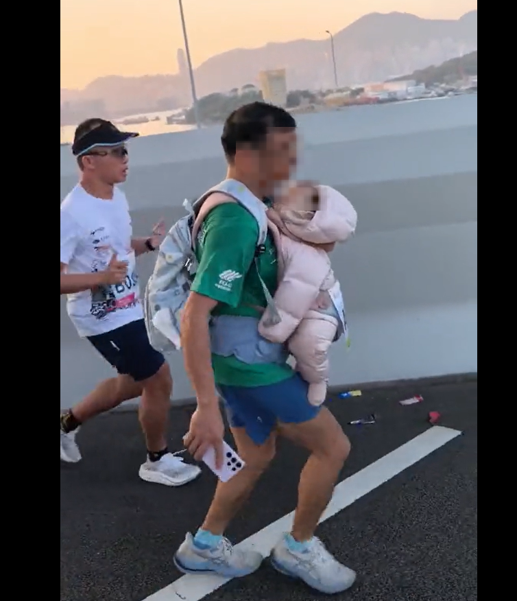 Screenshot from a video showing a man who ran in the Hong Kong marathon with a baby strapped to his front