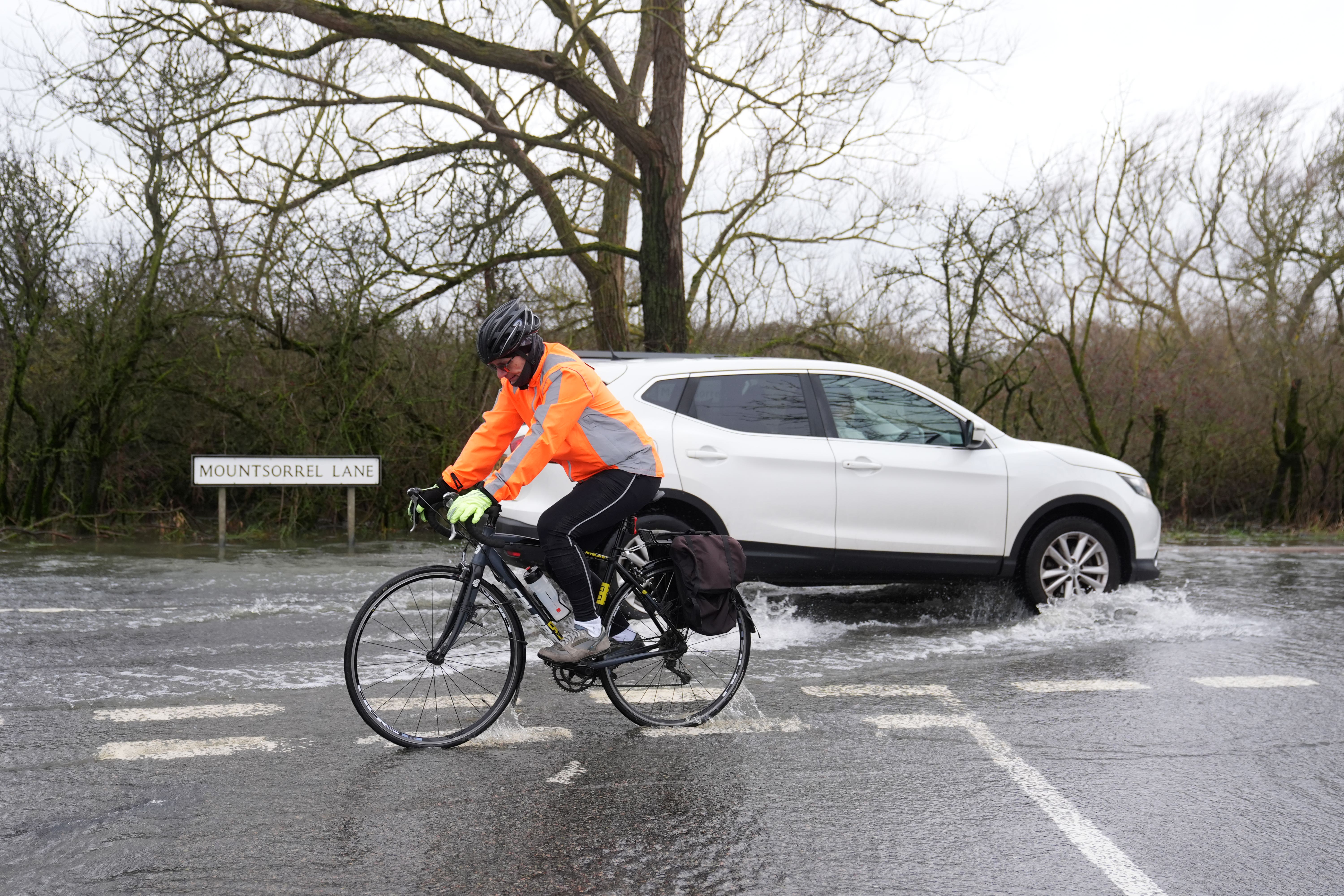 Cyclists and motorists navigate a flooded road in Mountsorrel, Leicestershire (PA)