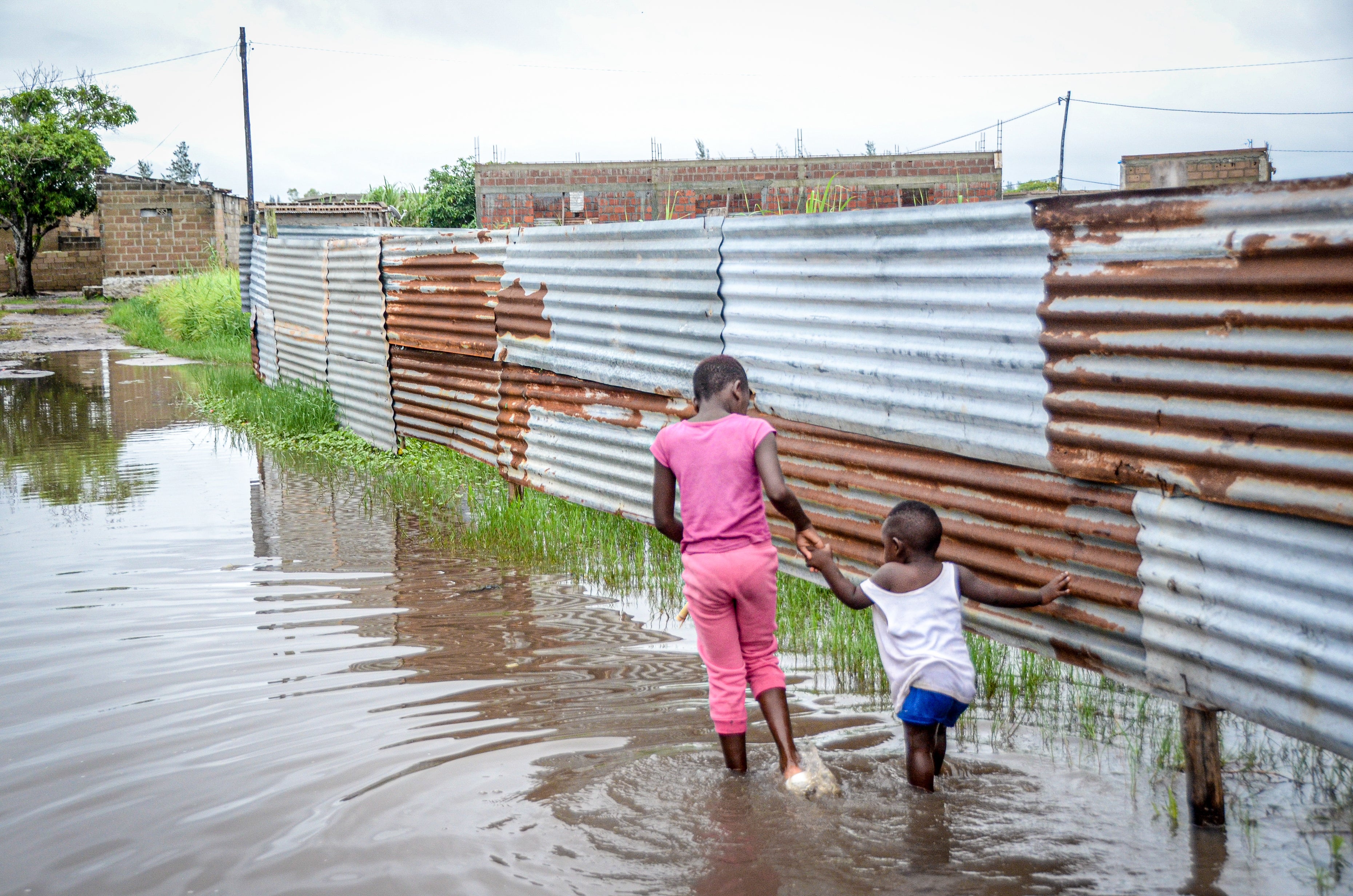 Children wade through floodwaters in a neighborhood in Maputo, Mozambique