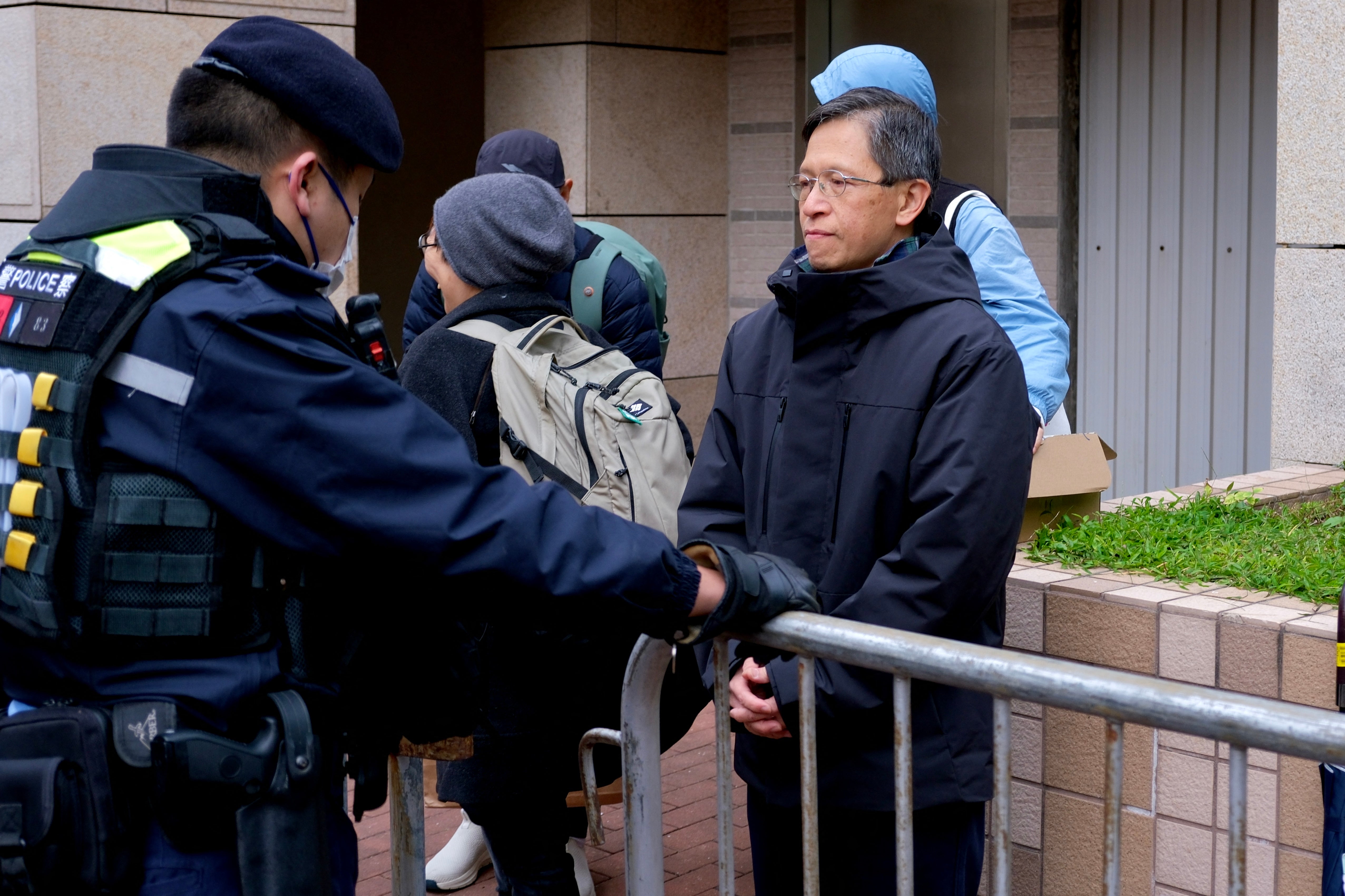 Tang Ngok-kwan (R), a Tiananmen vigil activist and former committee member for Hong Kong Alliance in Support of Patriotic Democratic Movements of China, is seen queueing for the start of the trial of the now-disbanded Hong Kong Alliance with among the defendants three of its leaders, Chow Hang-tung, Albert Ho and Lee Cheuk-yan who for years organised the annual vigil for the victims of the Tiananmen Square massacre in 1989