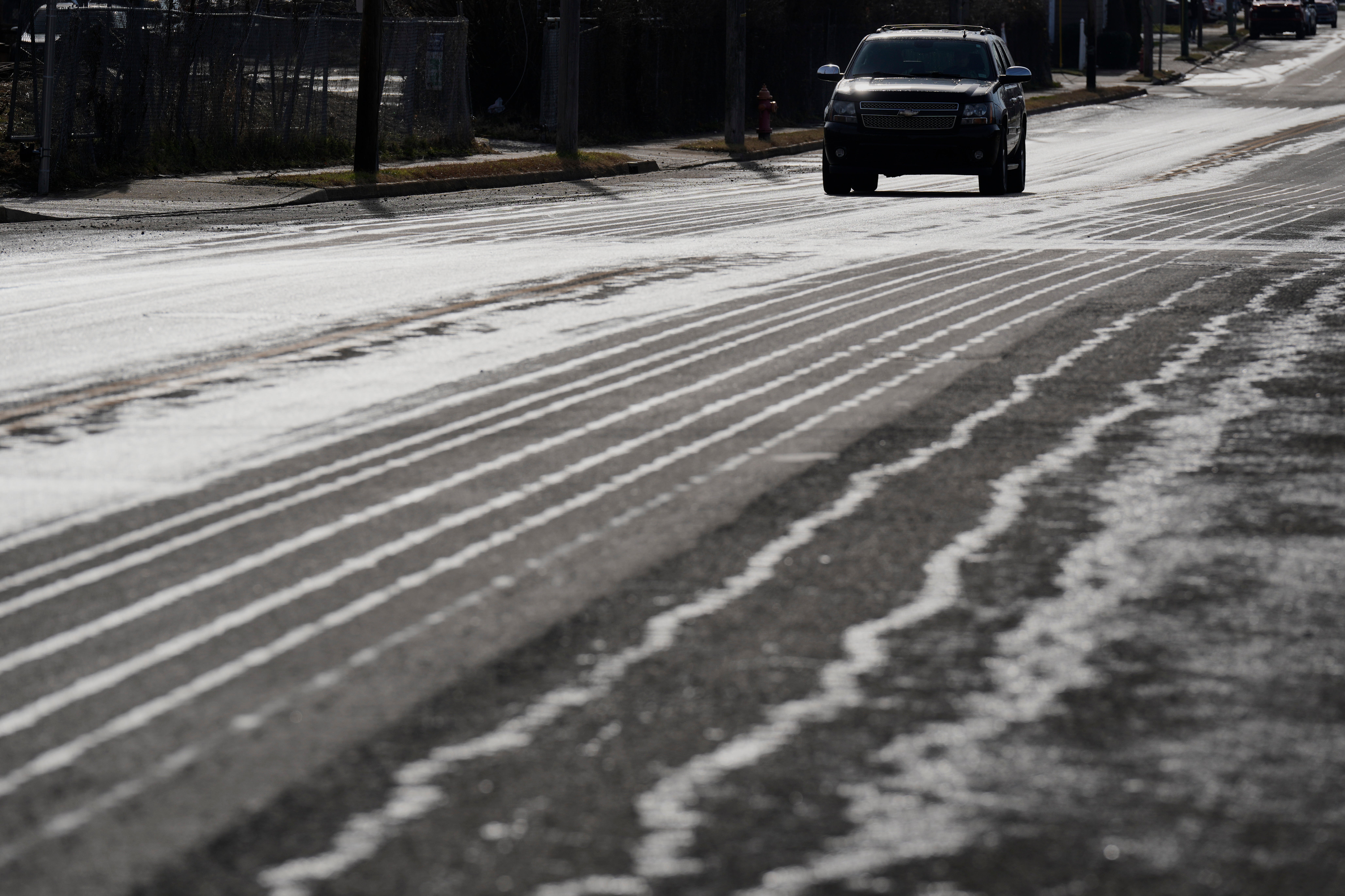 A car drives on a road in Tennessee treated with salt brine ahead of a devastating winter storm