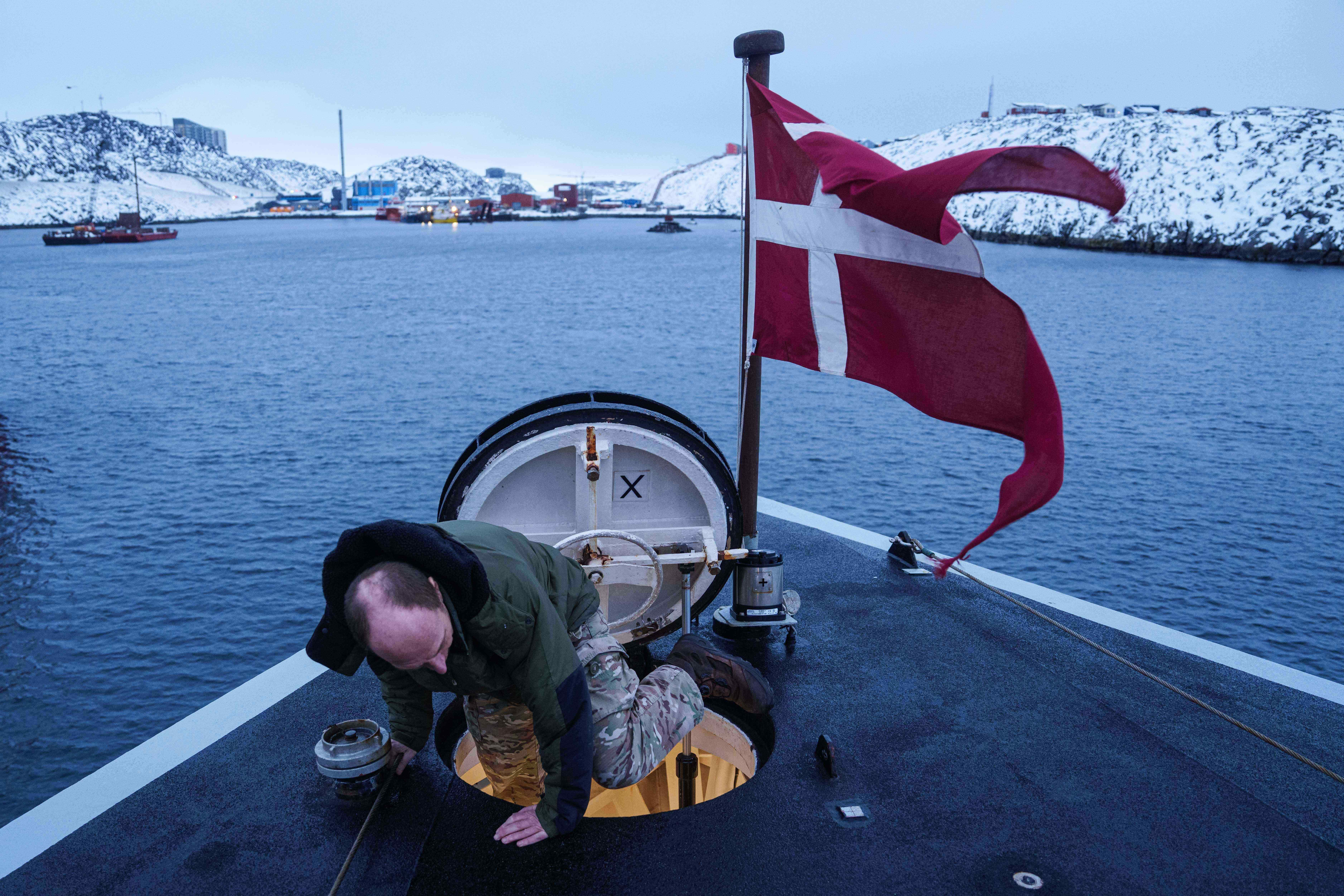 A Danish serviceman climbs out of a hatch on the bow of the military vessel HDMS Knud Rasmussen of the Royal Danish Navy docked in Nuuk, Greenland, on Saturday, Jan. 17, 2026. (AP Photo/Evgeniy Maloletka)